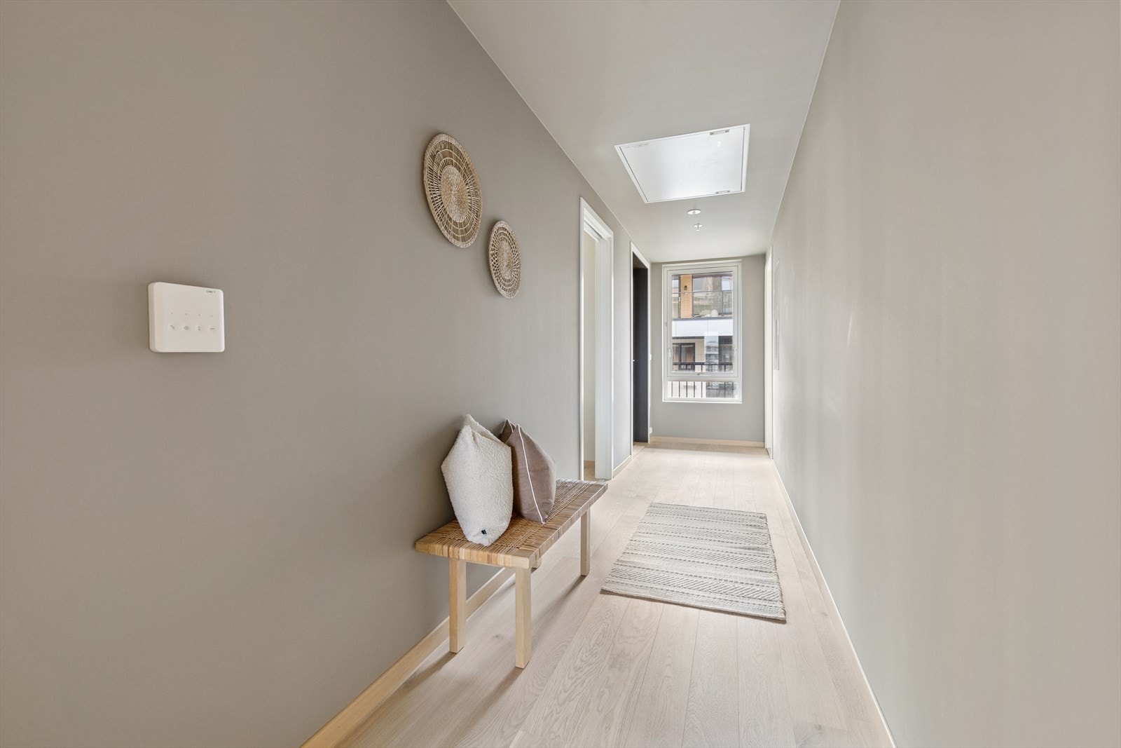 Lyst parkettgulv strekker seg gjennom entréen, som har slettmalte vegger for et rent uttrykk. Naturlig lys strømmer inn fra vinduet, og gir god belysning til rommet. Galleribilde