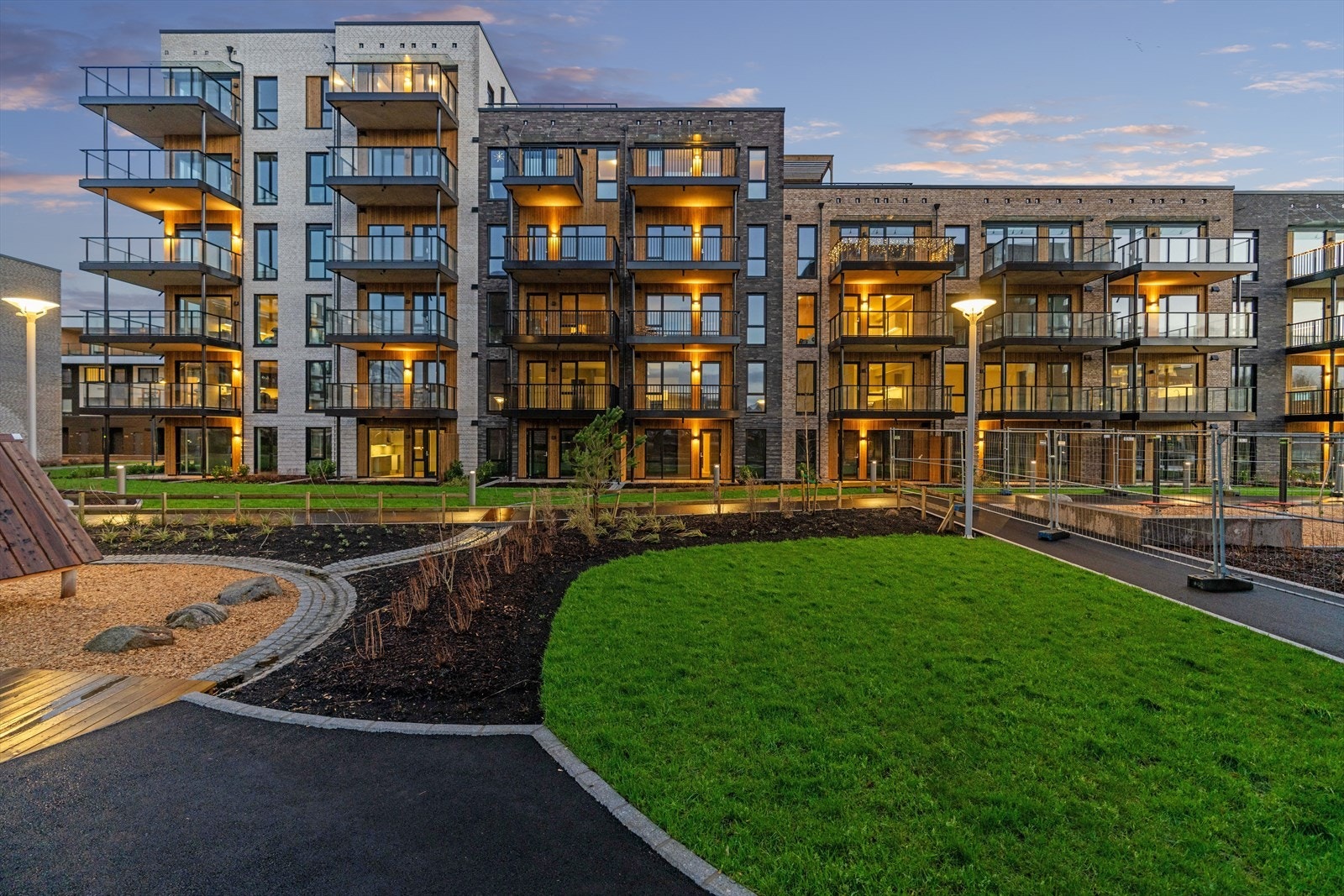 Leilighetskomplekset er opplyst om kvelden, med velholdt hage og gangstier. Galleribilde