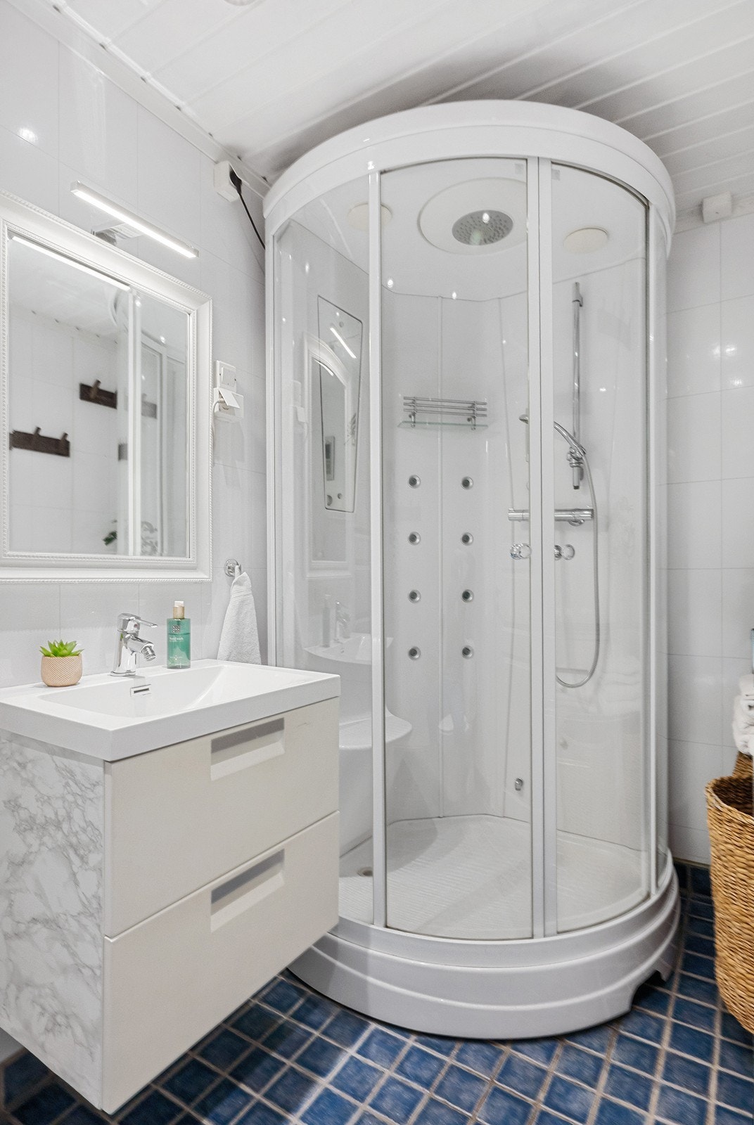 Badet er av ukjent alder og har behov for oppgraderinger etter dagens krav. Utstyrt med servant med underskap, speil med integrert belysning, dusjkabinett, vegghengt toalett og downlights i himling. Galleribilde