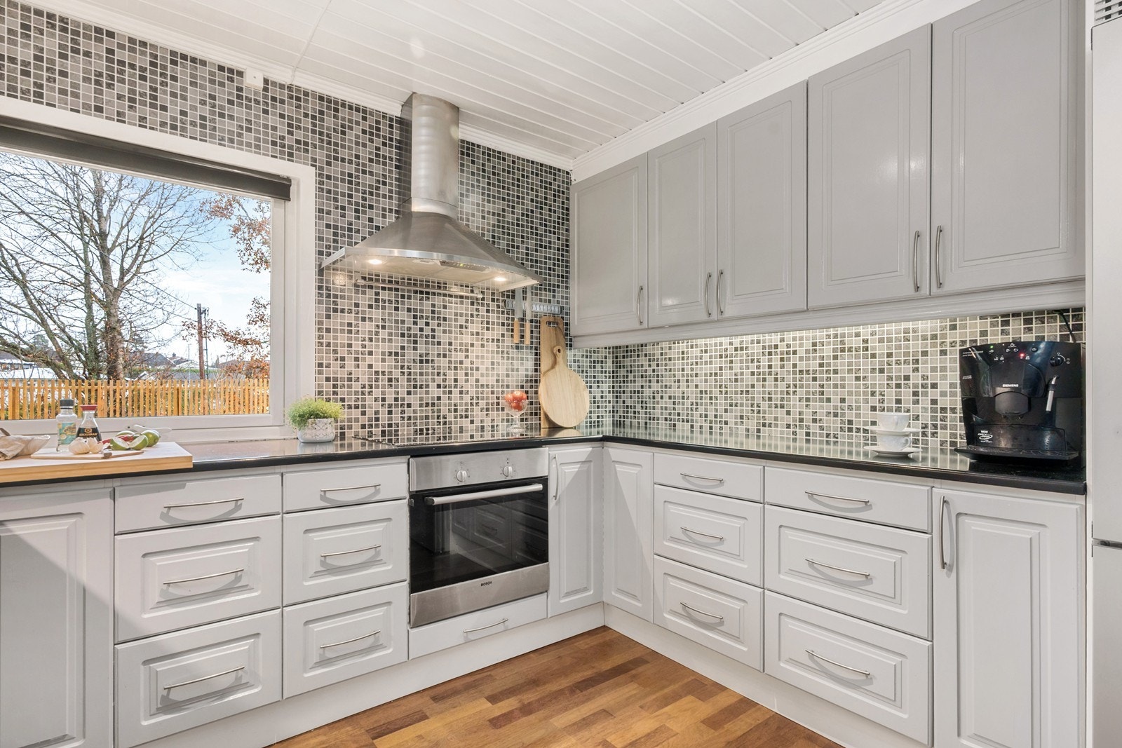 Innredningen har godt med skap- og benkeplass, og de profilerte frontene i gråtoner gir et pent uttrykk. Kjøkkenet har integrert platetopp og stekeovn, samt innbygget oppvaskmaskin. Galleribilde