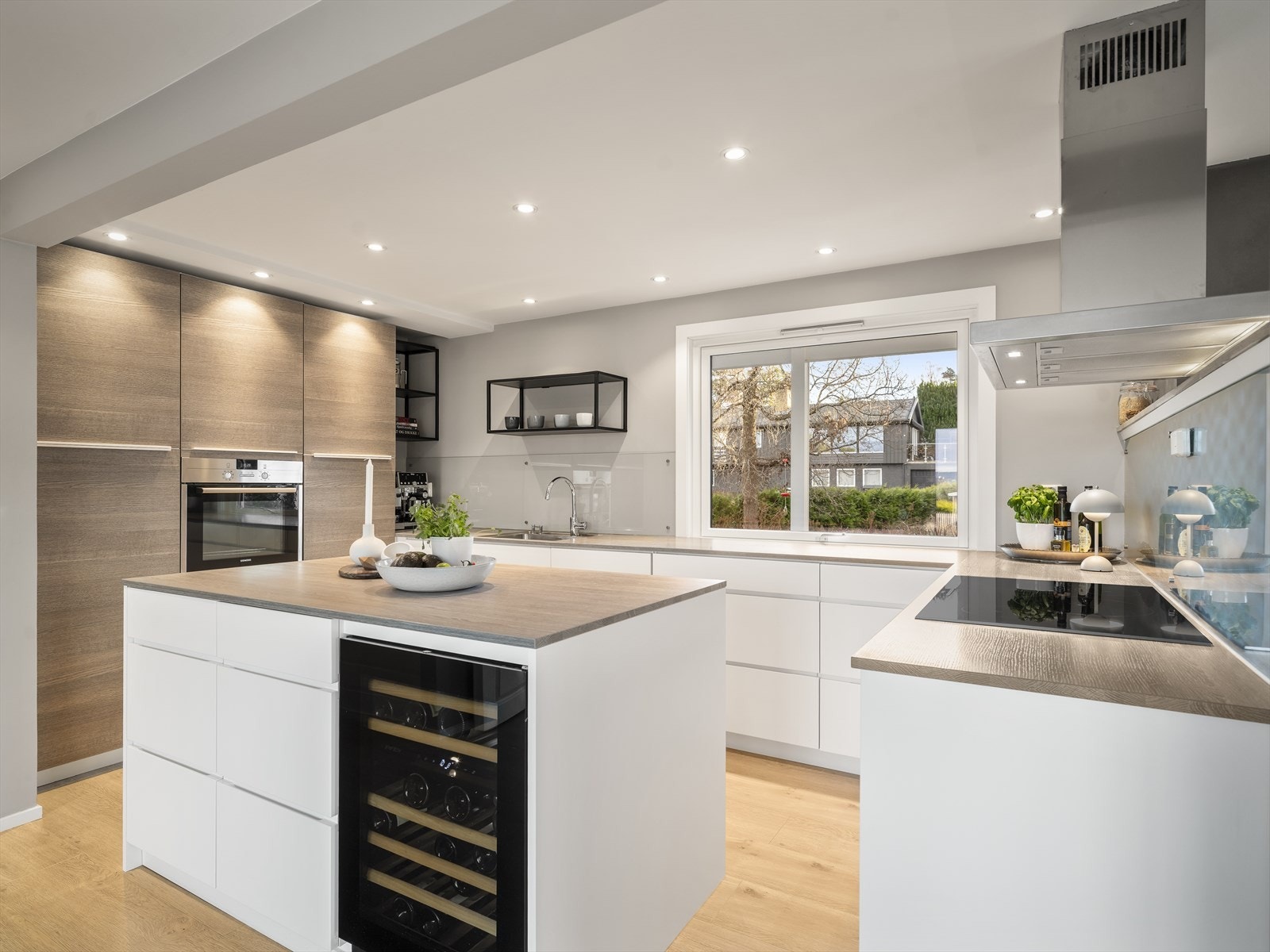 Romslig kjøkkenløsning som gir plass til både kokkekunst og hyggelige måltider. I himlingen er det montert downlights. Vinskap i kjøkkenøy Galleribilde