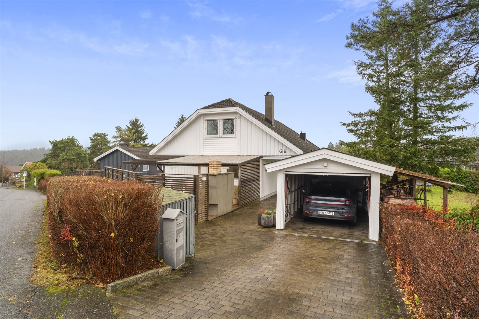 Innbydende fasade med opparbeidet gårdsplass. Garasje med to elbil ladere Galleribilde
