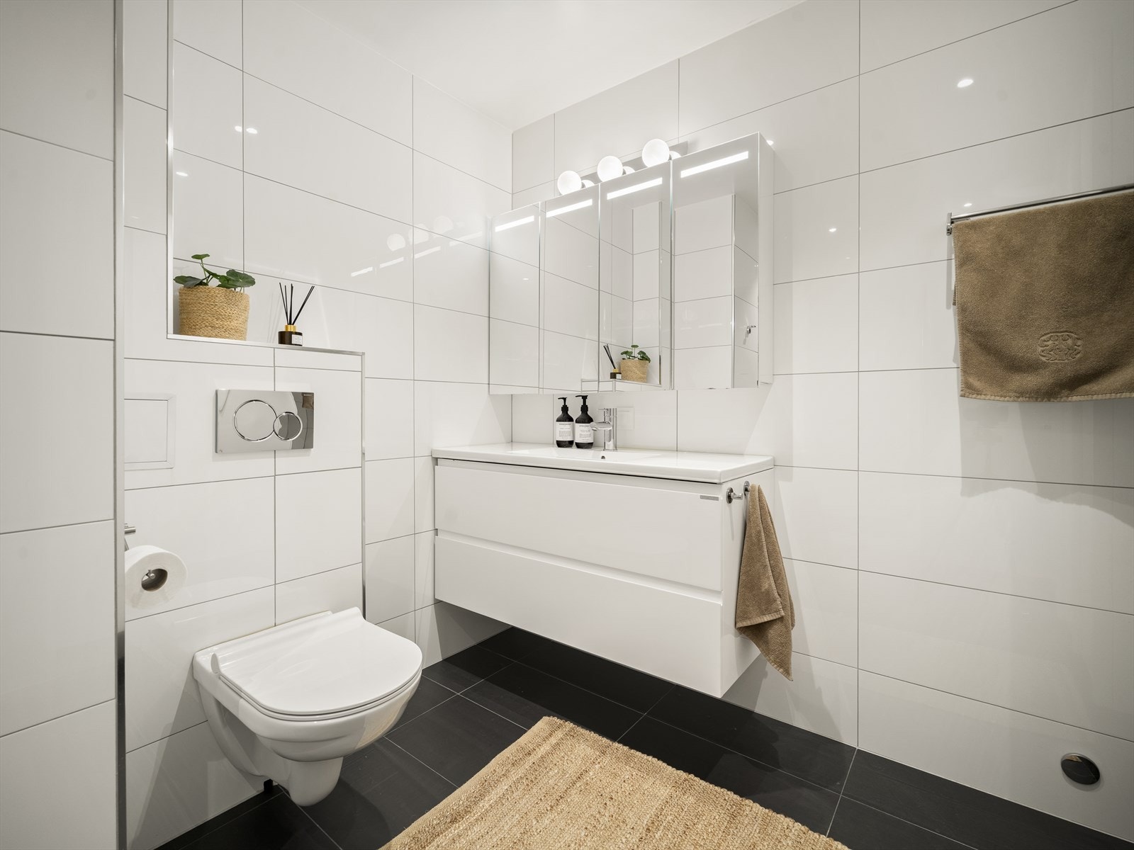 Badet er utstyrt med vegghengt toalett, vask med moderne innredning og dusjnisje med glassdører Galleribilde