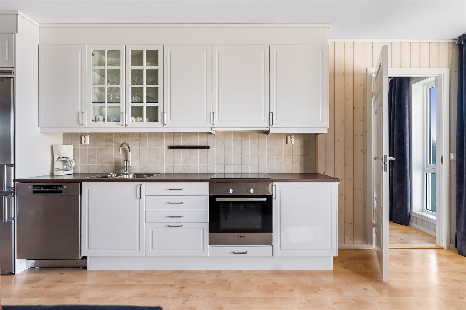 Det er flislagt og har belysning over benk. Kjøkkenet er utstyrt med integrert komfyr og koketopp, samt plass til frittstående oppvaskmaskin og kombiskap for kjøl/frys. Galleribilde