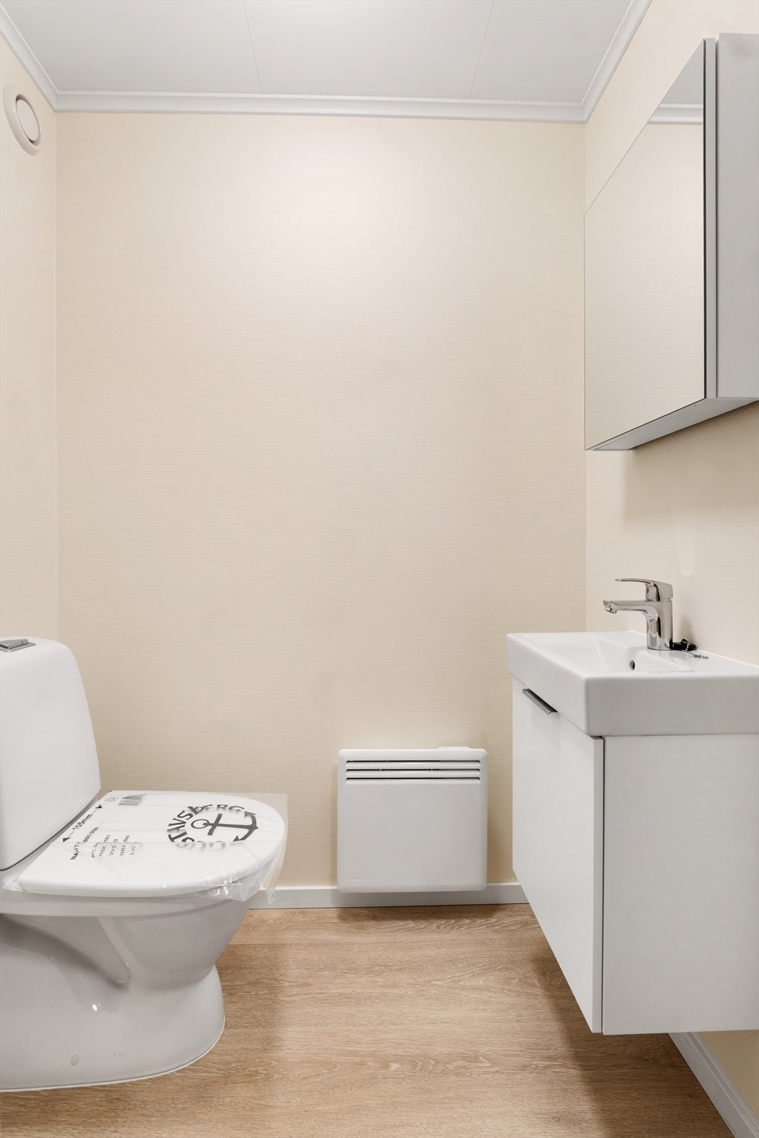 Toalettrommet har laminatgulv og vegger med strie - Her finner du gulvmontert toalett og innredning med nedfelt servant Galleribilde