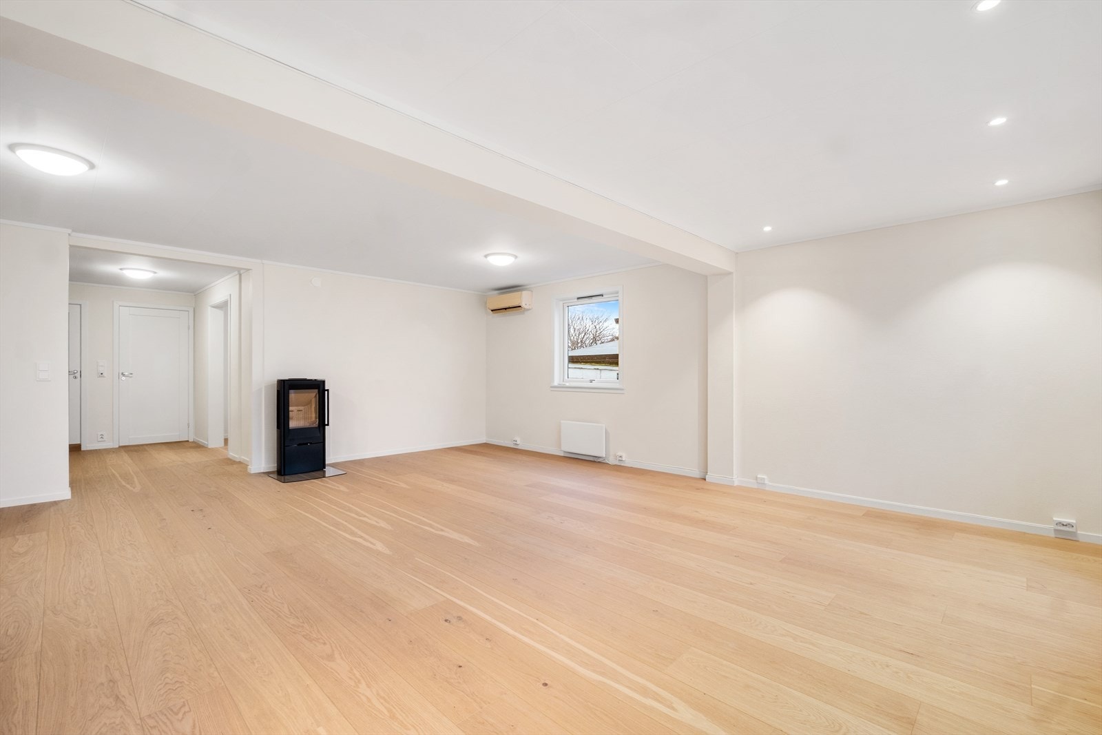 Den romslige stuen har en fint standard med et moderne gulv, lysmalte overflater og downlights i deler av taket Galleribilde