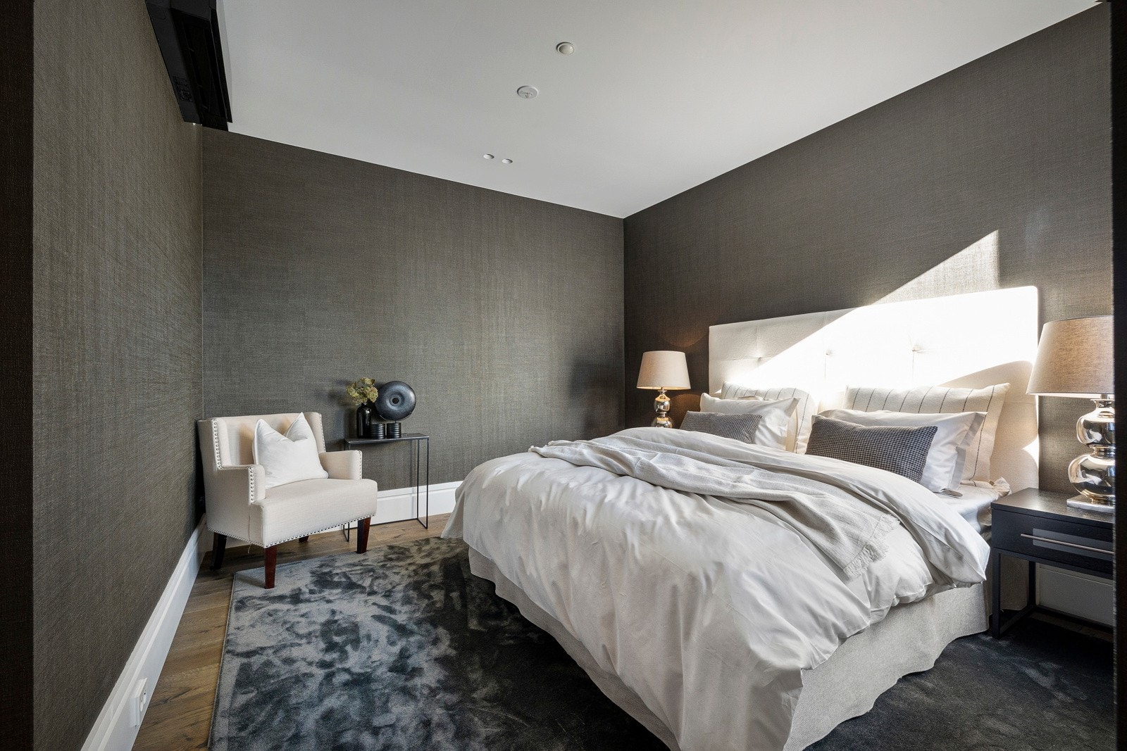 Veggene er kledd i en mørk og eksklusiv tapet med fin struktur, noe som bidrar til en intim og avslappende atmosfære. Galleribilde