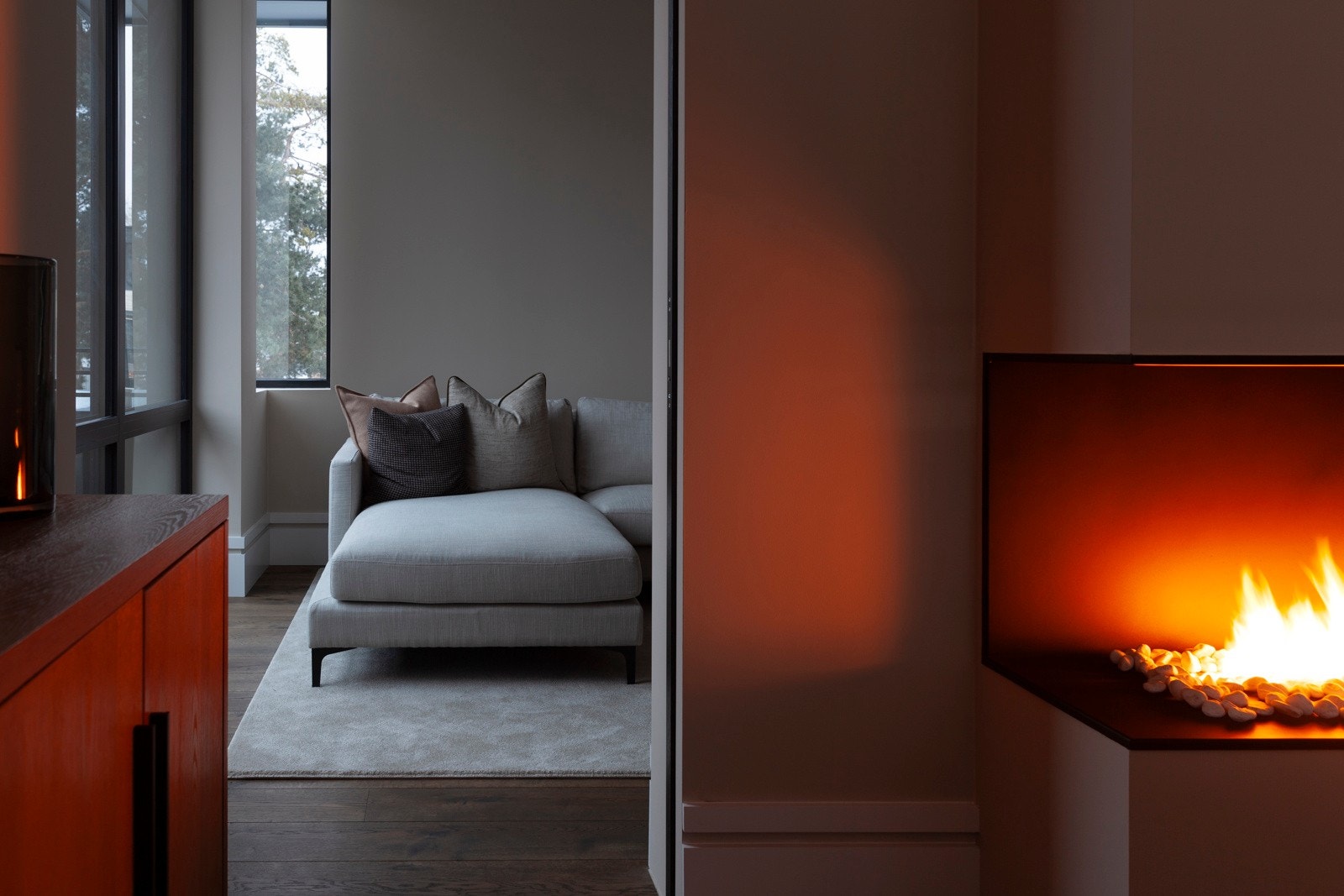 Stuen har en lun atmosfære med både gulvvarme og en stilren gasspeis som sklir sømløst inn i interiøret. Galleribilde