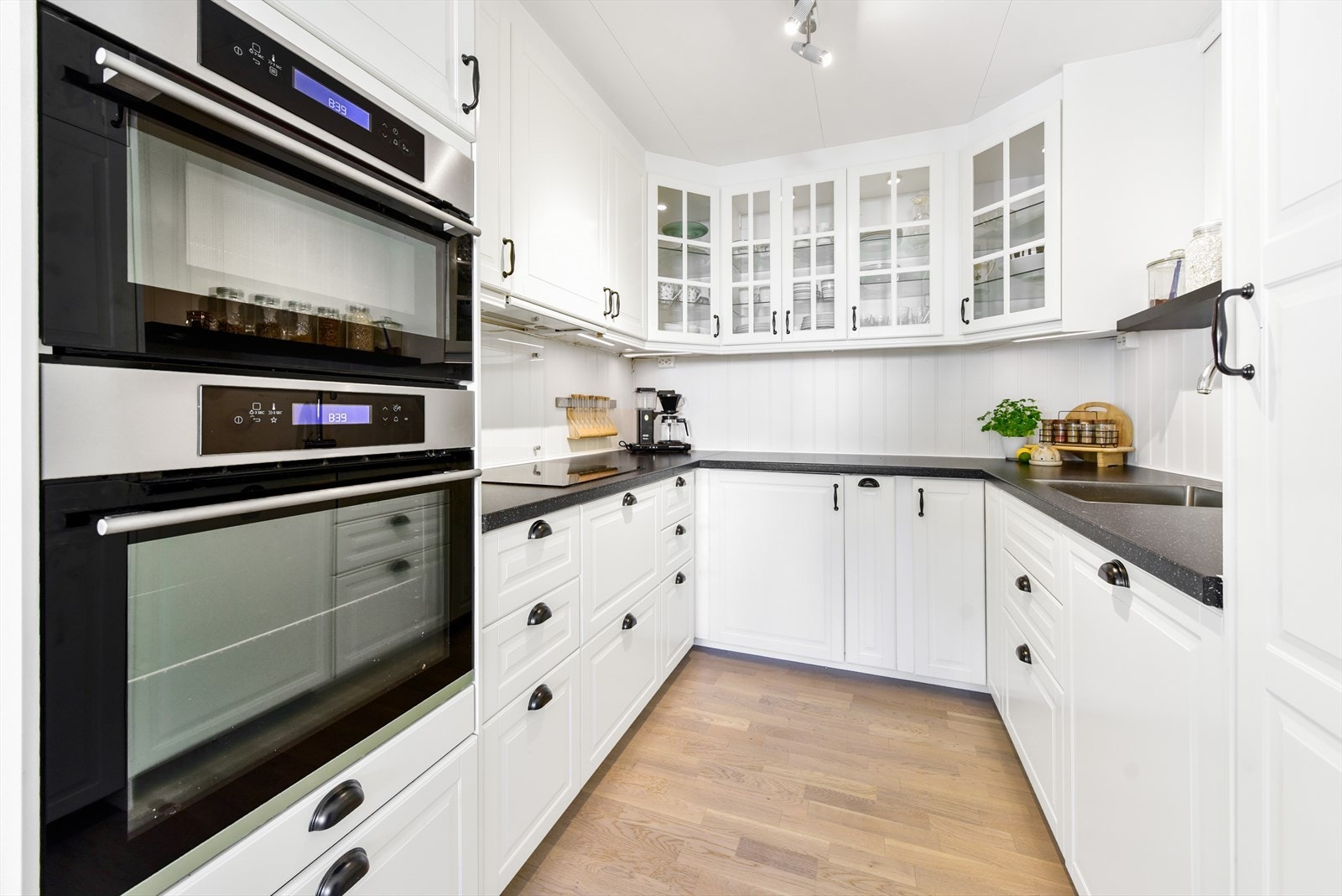 Kjøkkeninnredning utført med profilerte fronter og enkelte overskap med glassdører. Galleribilde