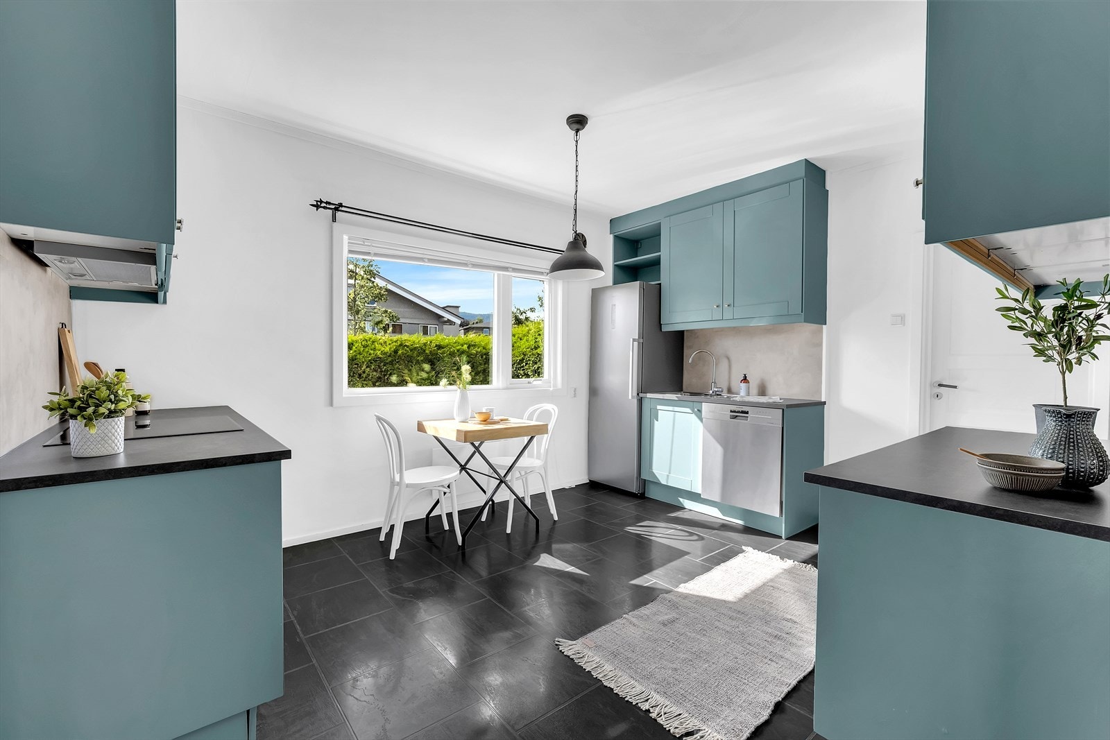 Det er oppvaskmaskin, induksjonstopp og stekeovn med beskyttelsesplate på vegg over benkeplate. Galleribilde