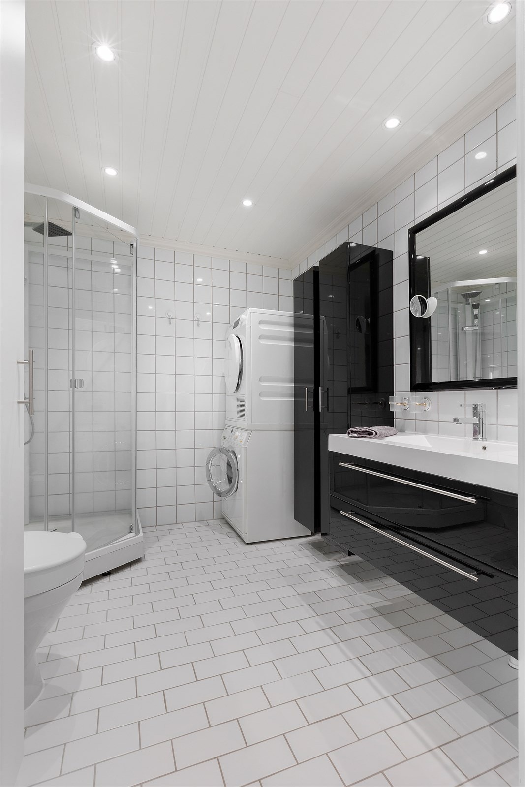 Rommet er innredet med heldekkende nedfelt servant med på tilhørende skuffeseksjon og høy skap, speil, toalett og dusjkabinett. Det er også opplegg for vaskemaskin og med plass til tørketrommel. Galleribilde