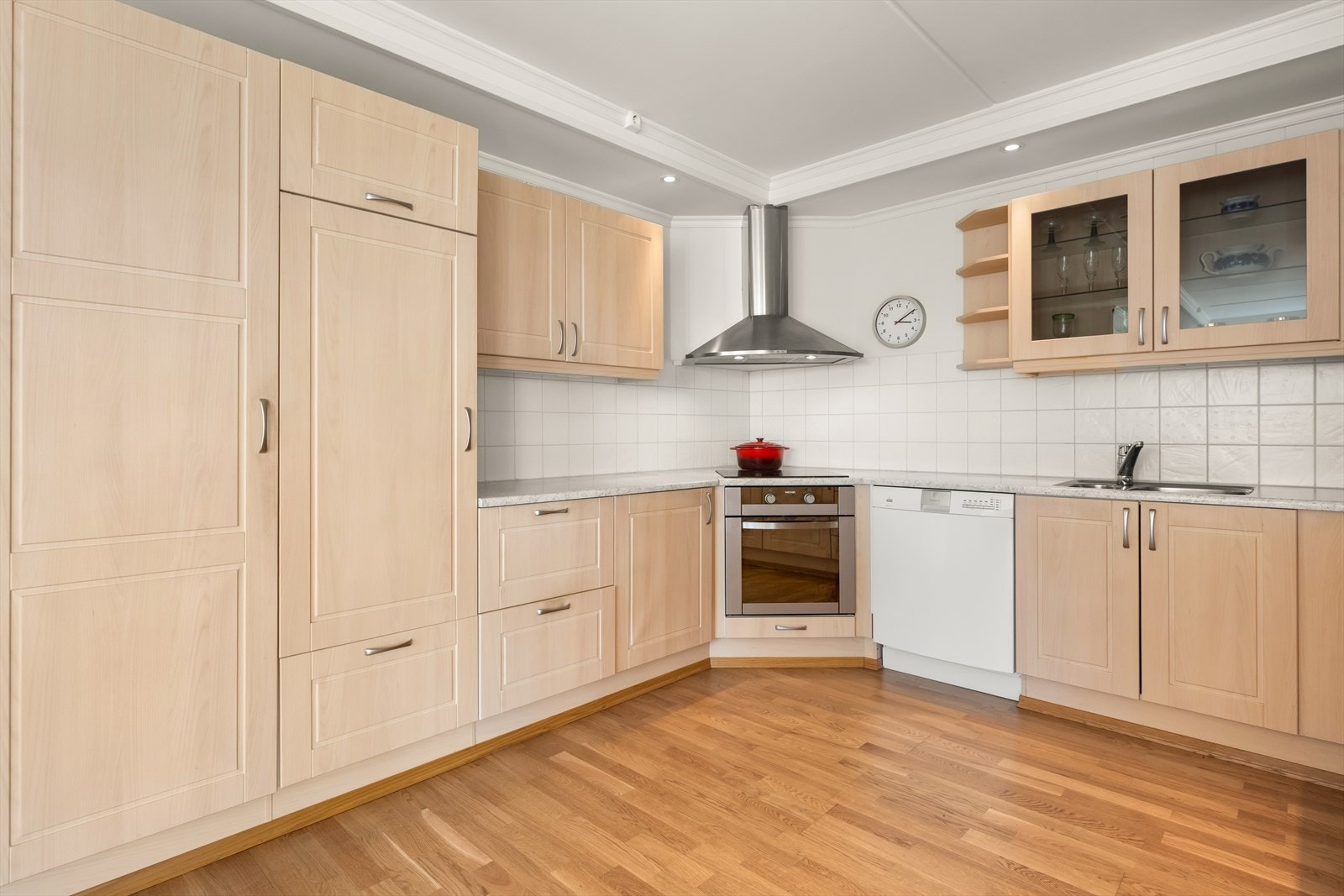 Romslig og pent kjøkken med fliser over benk, det er integrert kjøleskap, platetopp og stekeovn. Galleribilde