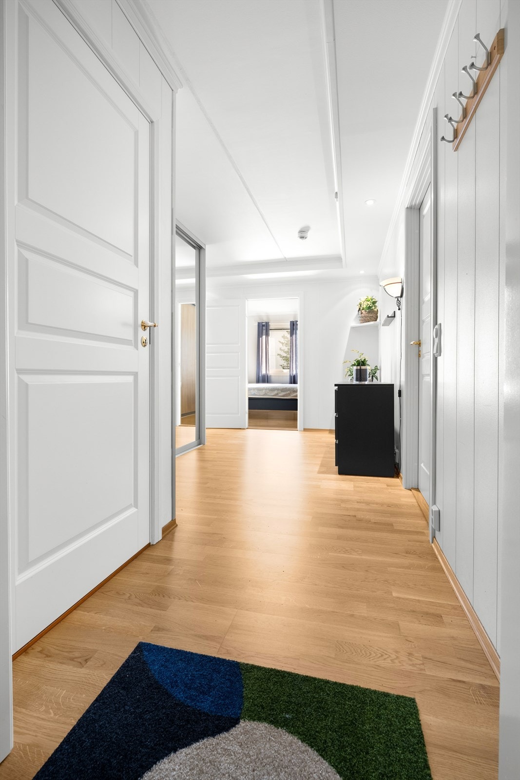 Lys gang med spotter i taket og knagger til oppbevaring av klær. Galleribilde