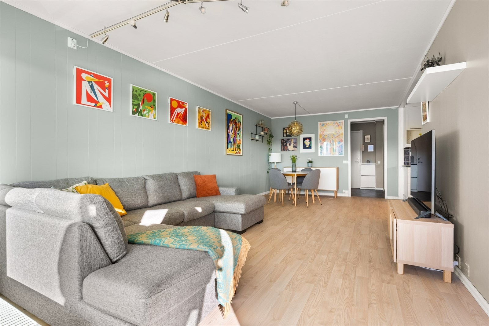 Lys og delikat stue med parkett på gulv og slette vegger malt i en trendy og dus grønntone. Galleribilde