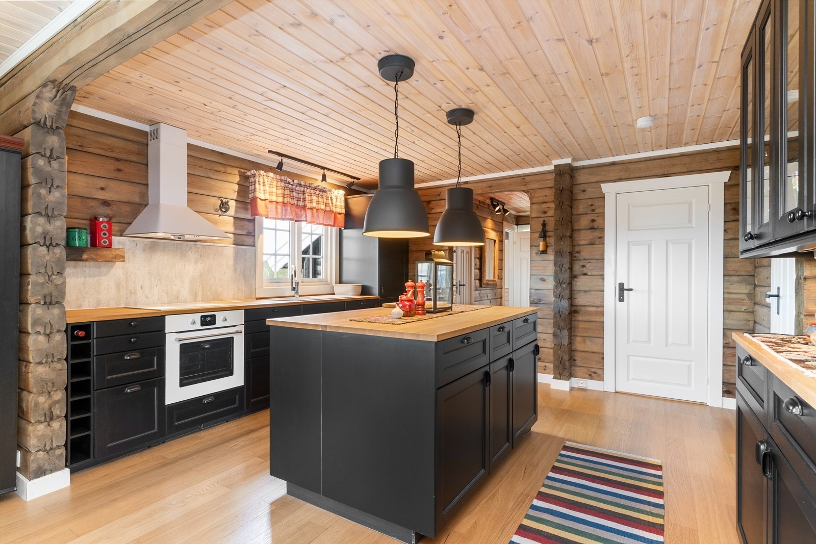 Kjøkkenet byr på en praktisk utforming med mye benkeplass, mørke profilerte fronter og benkeplate i heltre. Galleribilde