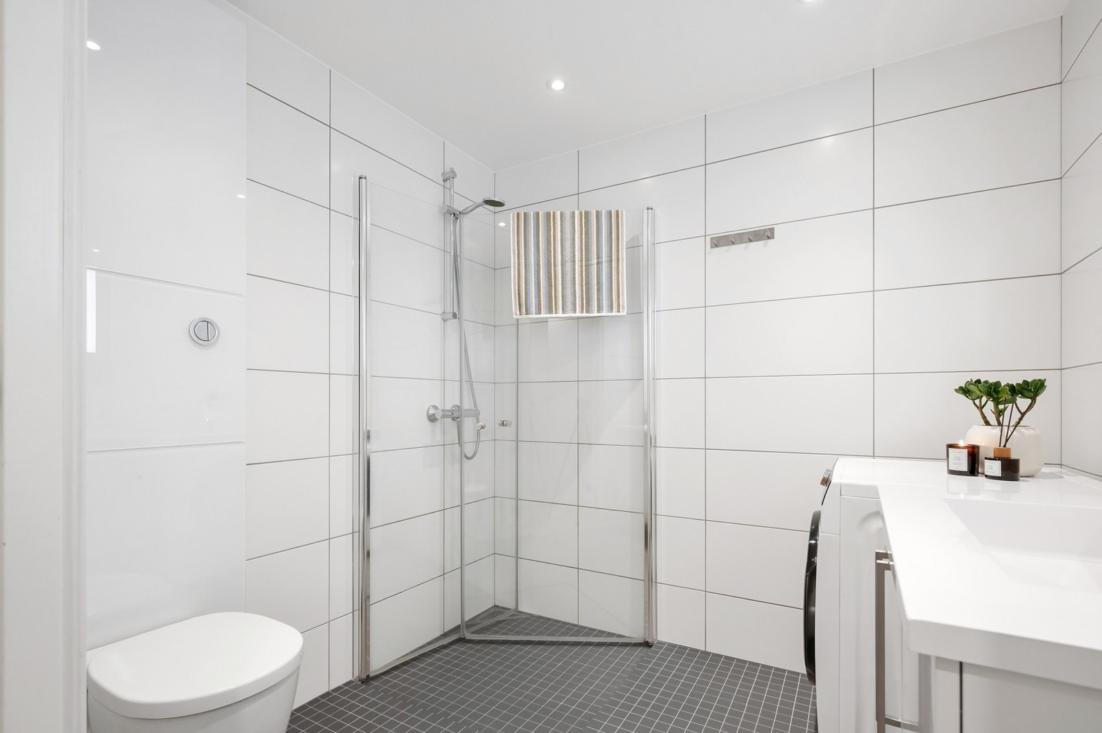 Badet er innredet med dusjhjørne med 2 stk dusjdører, veggmontert WC, servant montert på underskap og speil. Galleribilde