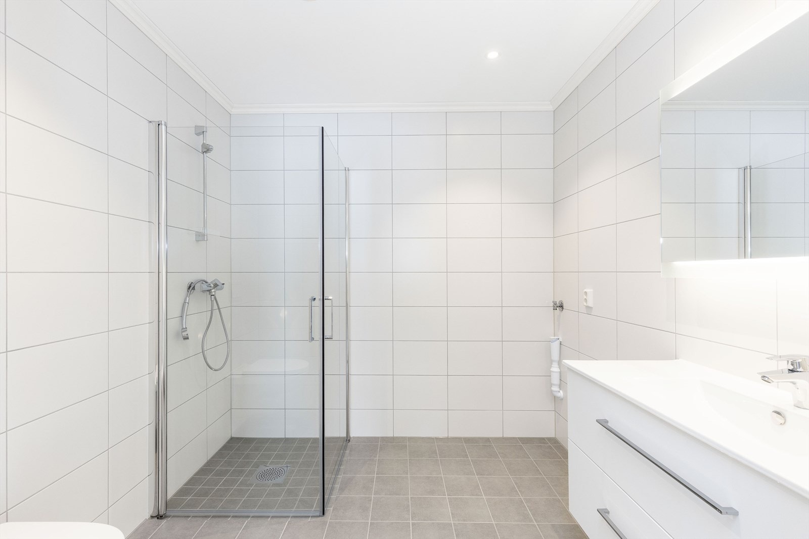 Romslig og flislagt bad med dusjhjørne og opplegg til vaskemaskin Galleribilde