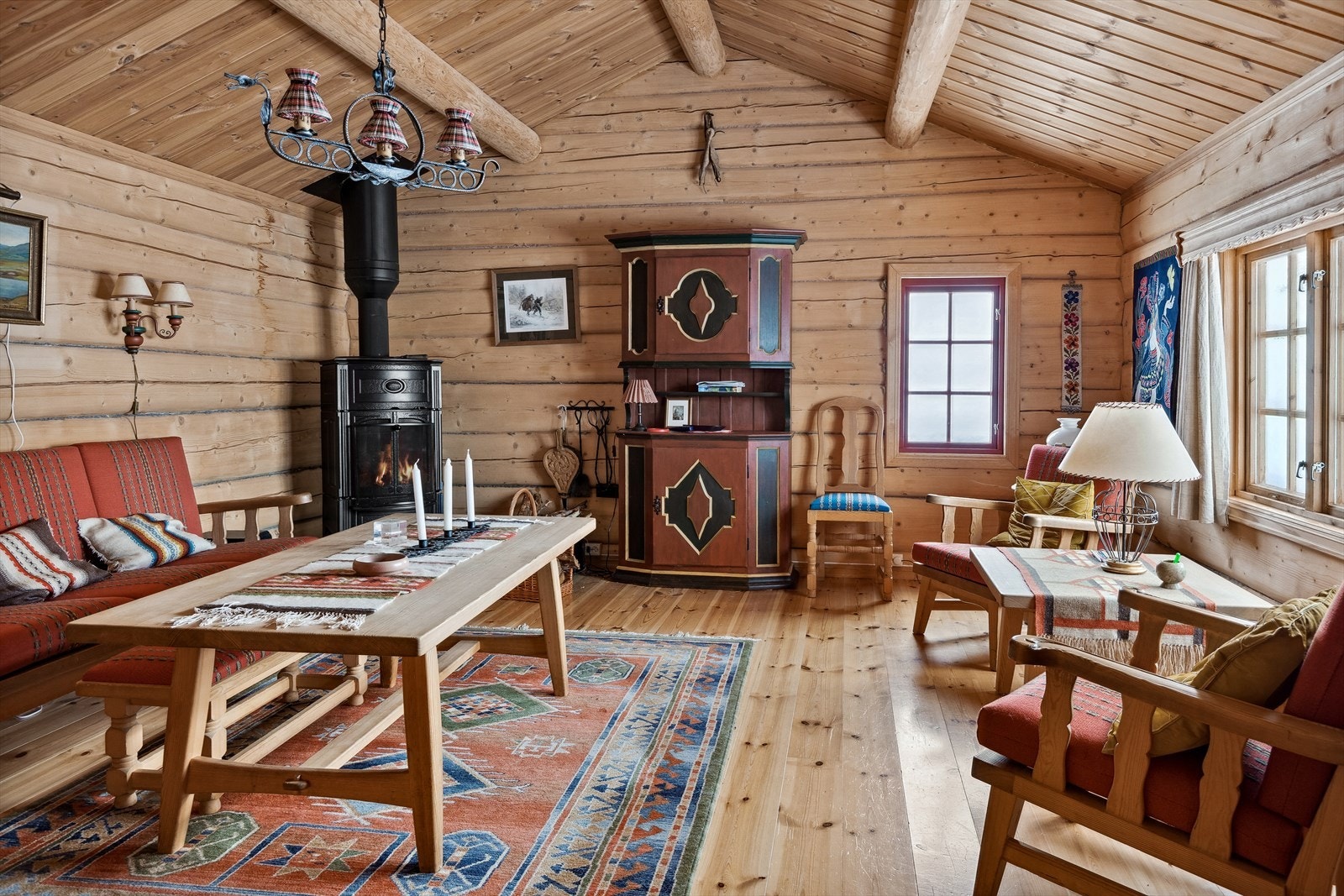 Hyggelig tømmerstue med en plassbygd liten bar. Åstak med synlige rundåser som gir god romfølelse. Stuen inneholder også en vedovn med glassdør for oppvarming. Galleribilde