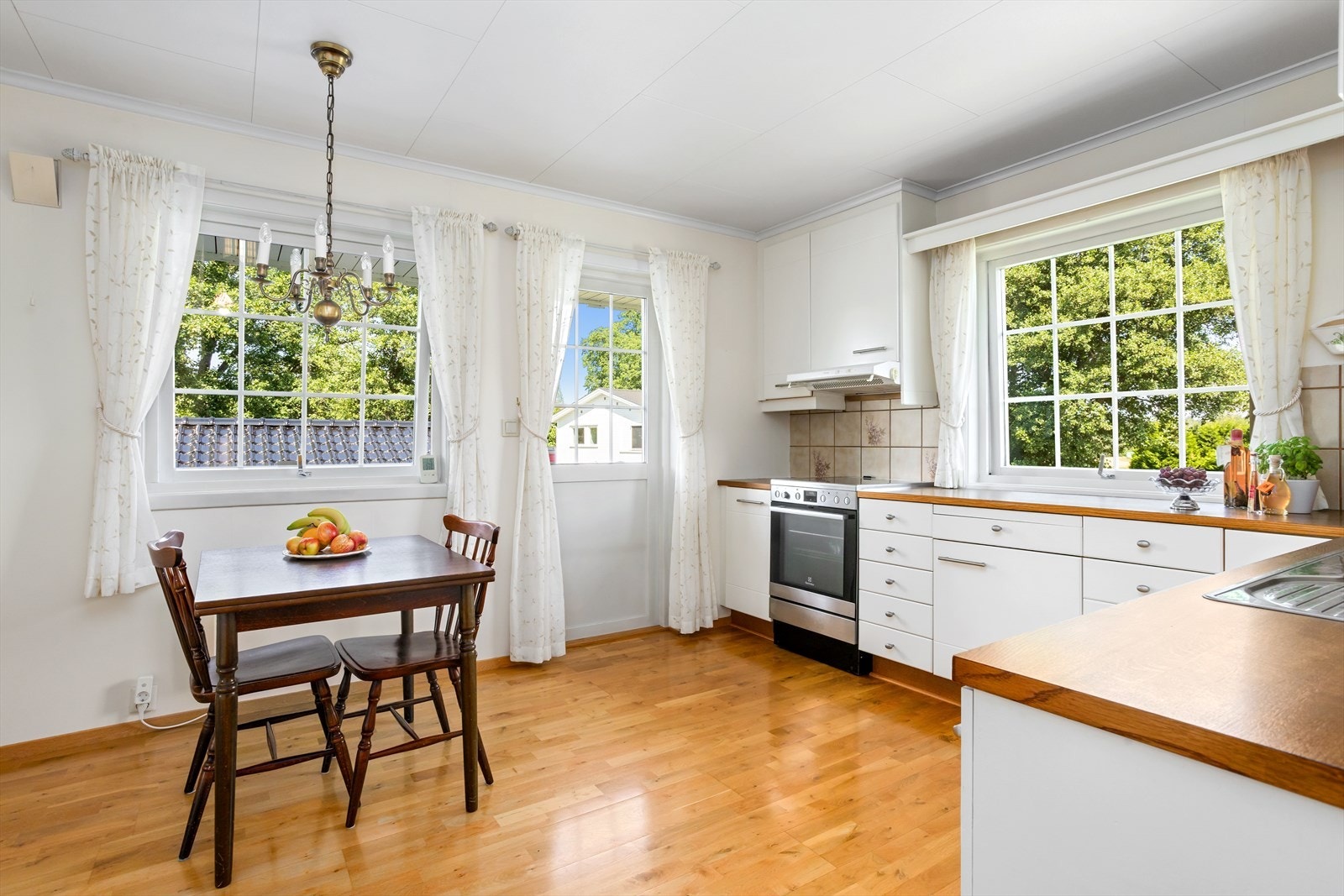 Også kjøkkenet har direkte utgang til eiendommens flotte terrassearrangement. Kjøkkenet ligger på hushjørnet i motsatt ende av hovedstuen hvor vinduene i rommet slipper inn morgensolen. Galleribilde