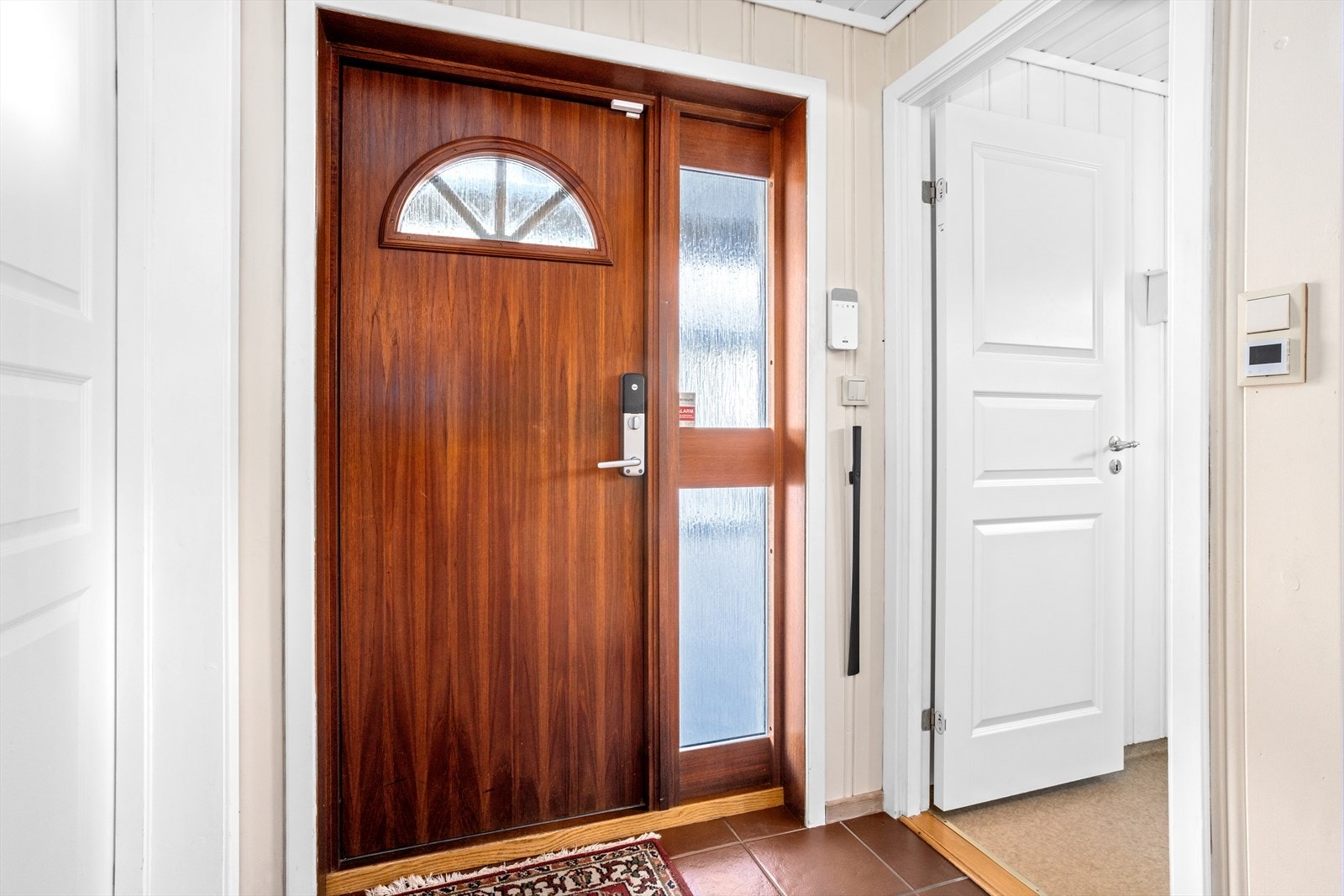 Den noe inntrukne og overbygde bygningskroppen ved inngangspartiet skjermer ytterdøren av teak for vind og nedbør. Galleribilde