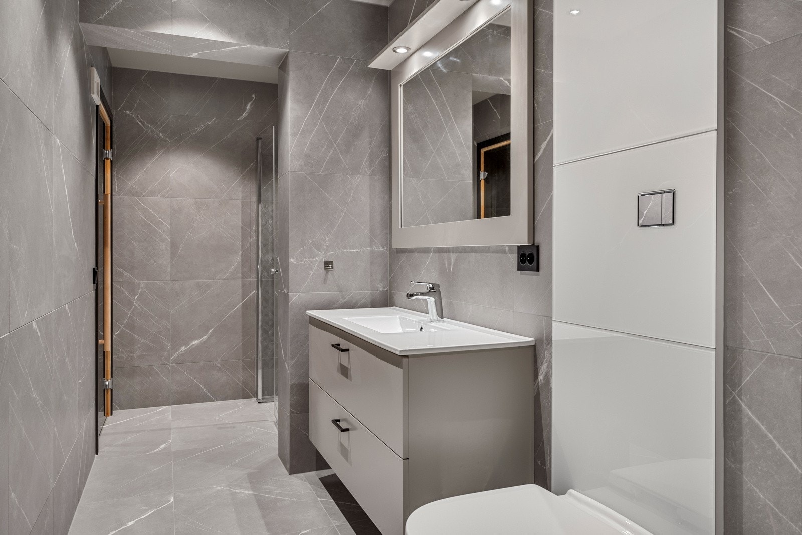 Det andre badet er svært delikat med lekre fliser på gulv og vegg, downlights i himlingen, dusjnisje med glassdører og regnfallsdusj, samt vegghengt wc. Galleribilde