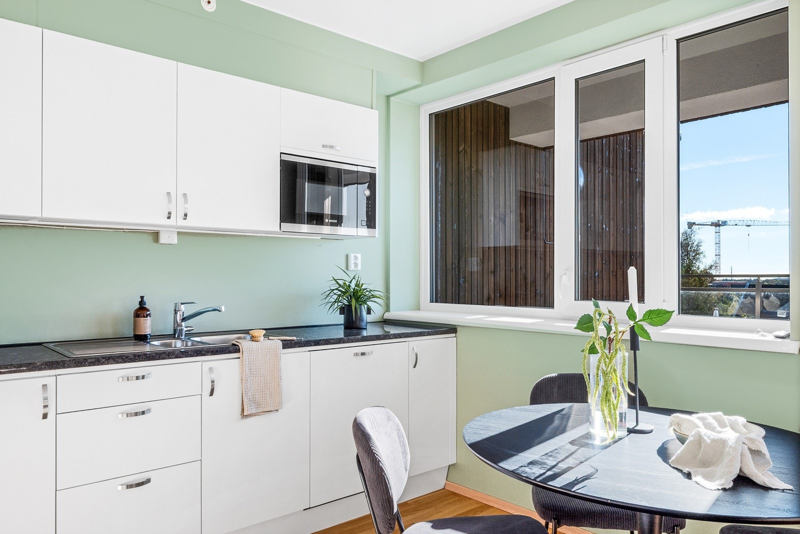 Det moderne kjøkkenet har alt du trenger fordelt på to vegger. Innredningen har hvite, slette fronter og mørk kvarts benkeplate med nedfelt kum. Galleribilde