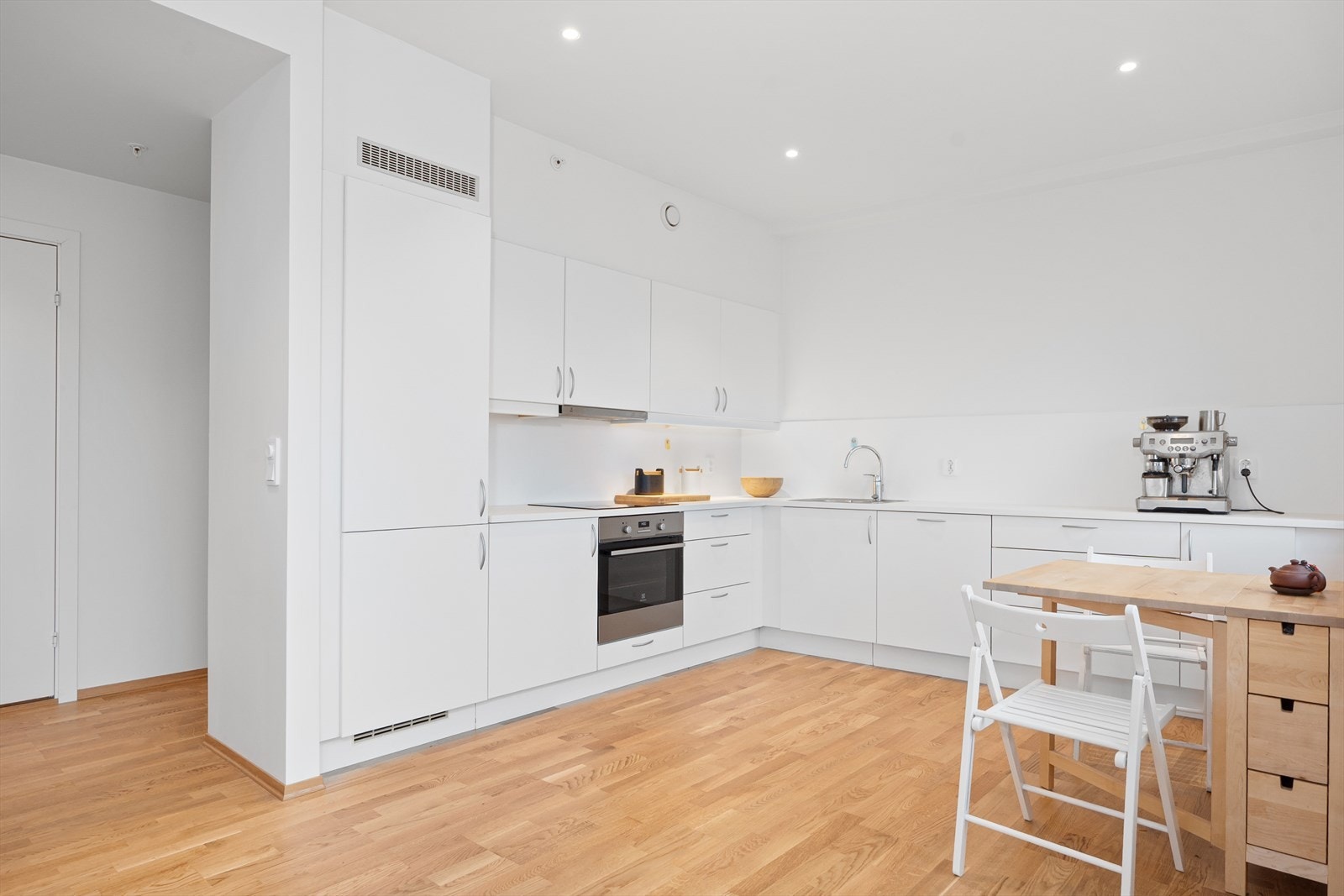 Kjøkkenet er funksjonelt utformet med god benkeplass, hvite slette fronter og høyskap på den ene veggen. Galleribilde