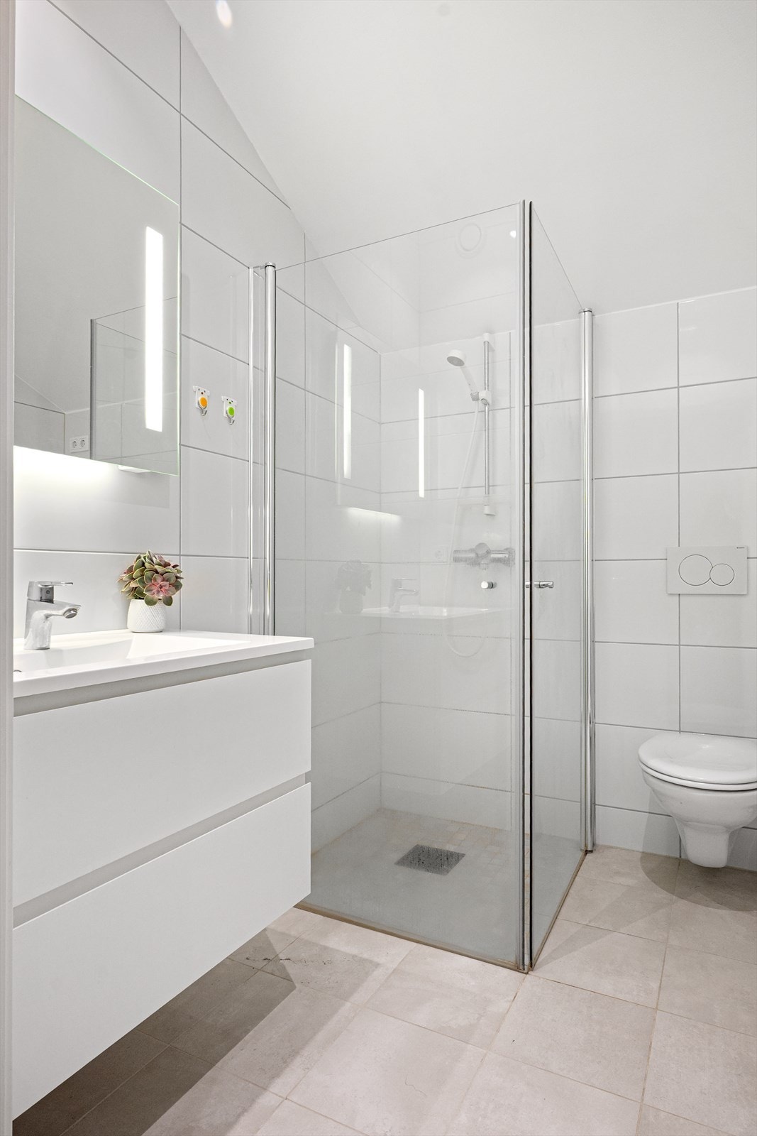 Moderne innredning med dusjhjørne med innfellbare glassdører, vegghengt toalett og servant med skuffeløsning. Galleribilde