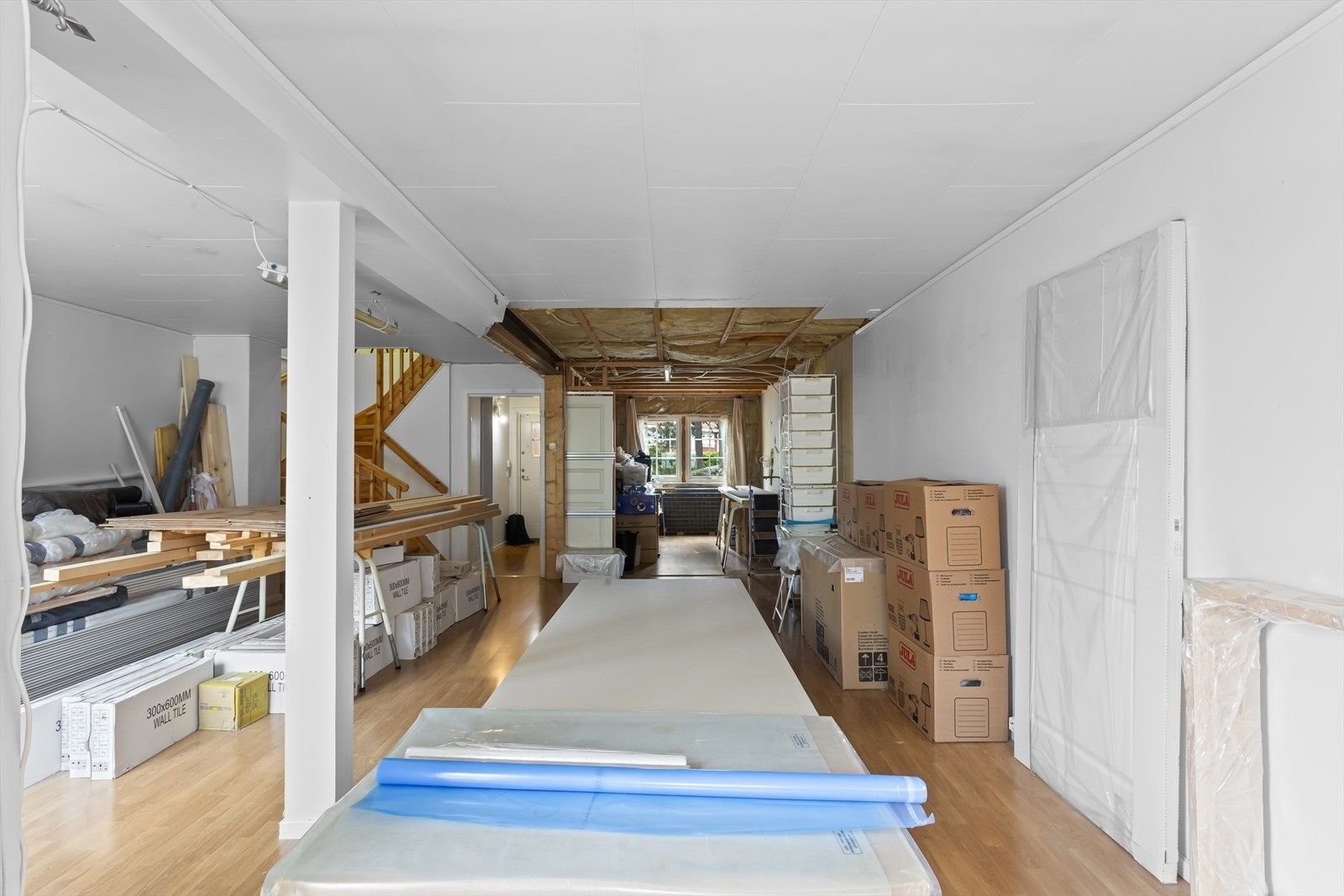 Innerst til høyre vises kjøkken som er revet og klargjort for oppussing. Man kan ha en vegg mellom kjøkken stuen, eller ha en åpen kjøkken-/stueløsning. Bildet viser også stuen der oppussingsmaterialene er plassert, som kan innredes etter ønske og behov. Galleribilde