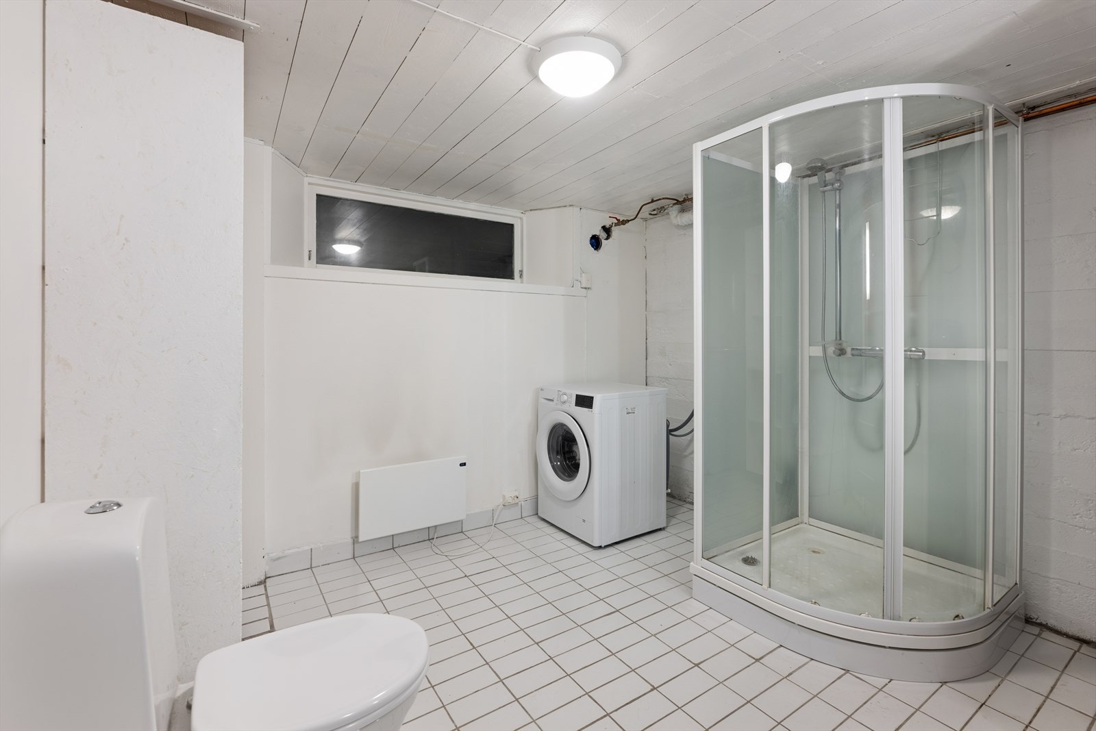 Baderommet i kjelleren er opprinnelig et vaskerom som ble omgjort i 2018 og enkelt innredet uten membran med flislagt gulv og malte flater. Galleribilde