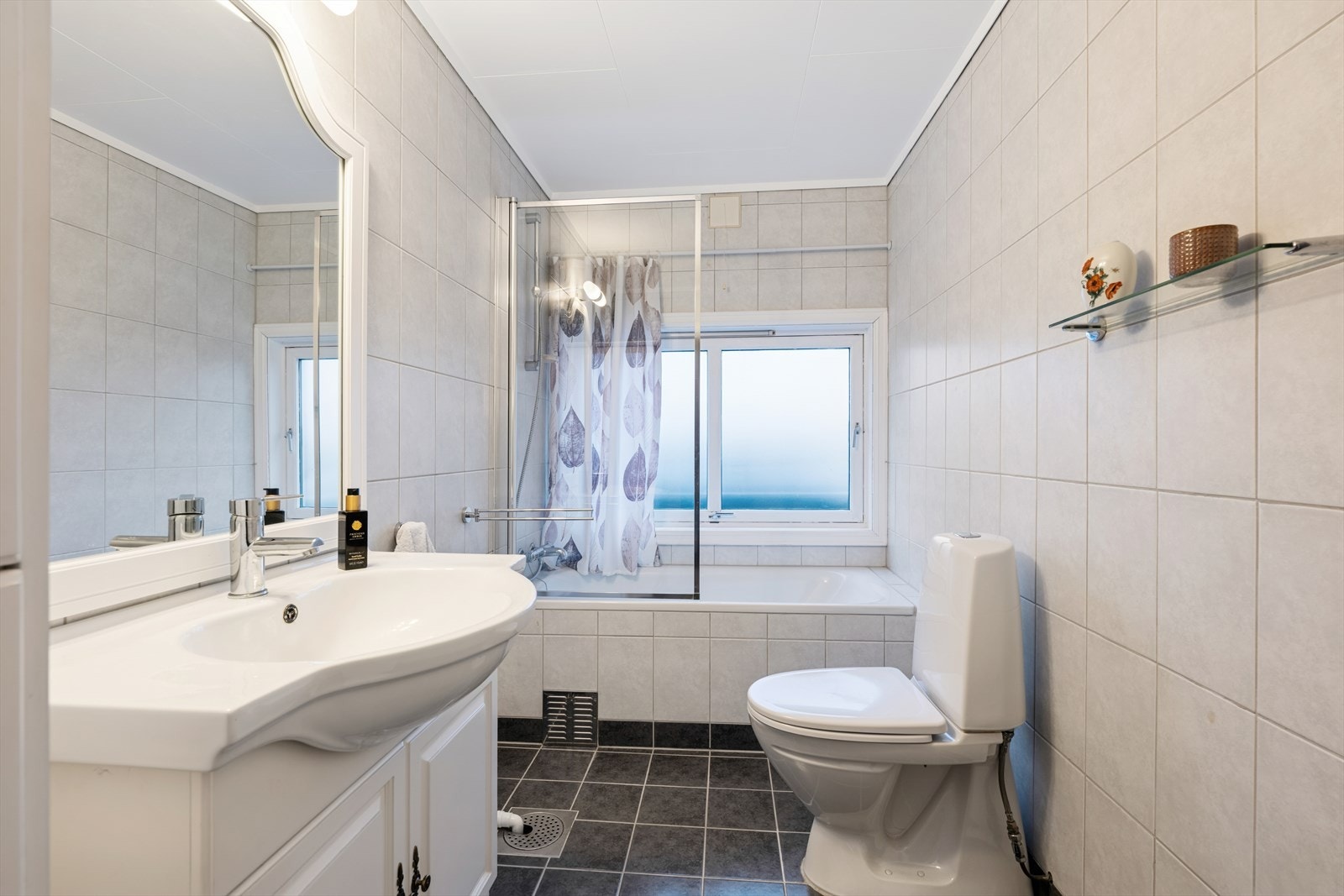 Det ene baderommet er innredet med grå fliser på gulv og lyse fliser på vegg. I gulvet har man også varmekabler for ekstra komfort. Galleribilde