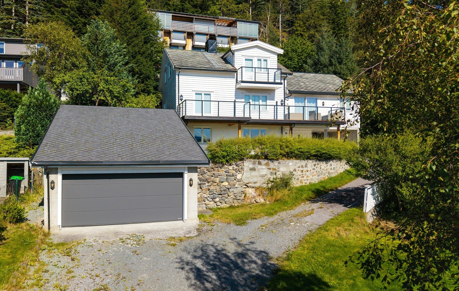 Fasade mot sør som viser adkomstvei, garasje og bolighuset Galleribilde