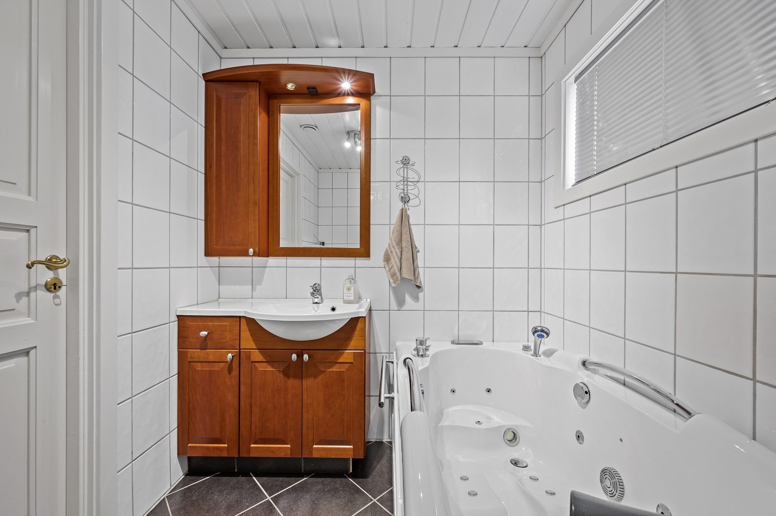 Badet er utstyrt med badekar og servant med tilhørende speil og skap. Galleribilde