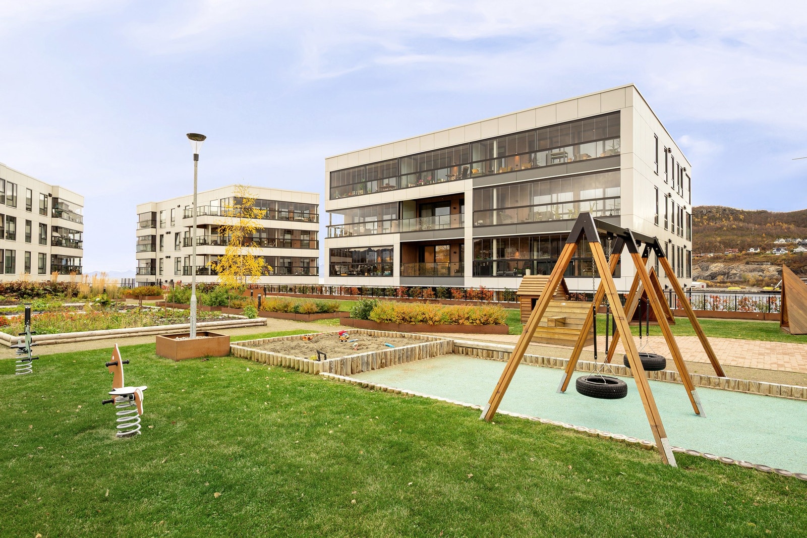 Nyere leilighetsbygg med parkanlegg utenfor med lekeplass, husker og sandkasse, og selvfølgelig sittebenker! Galleribilde