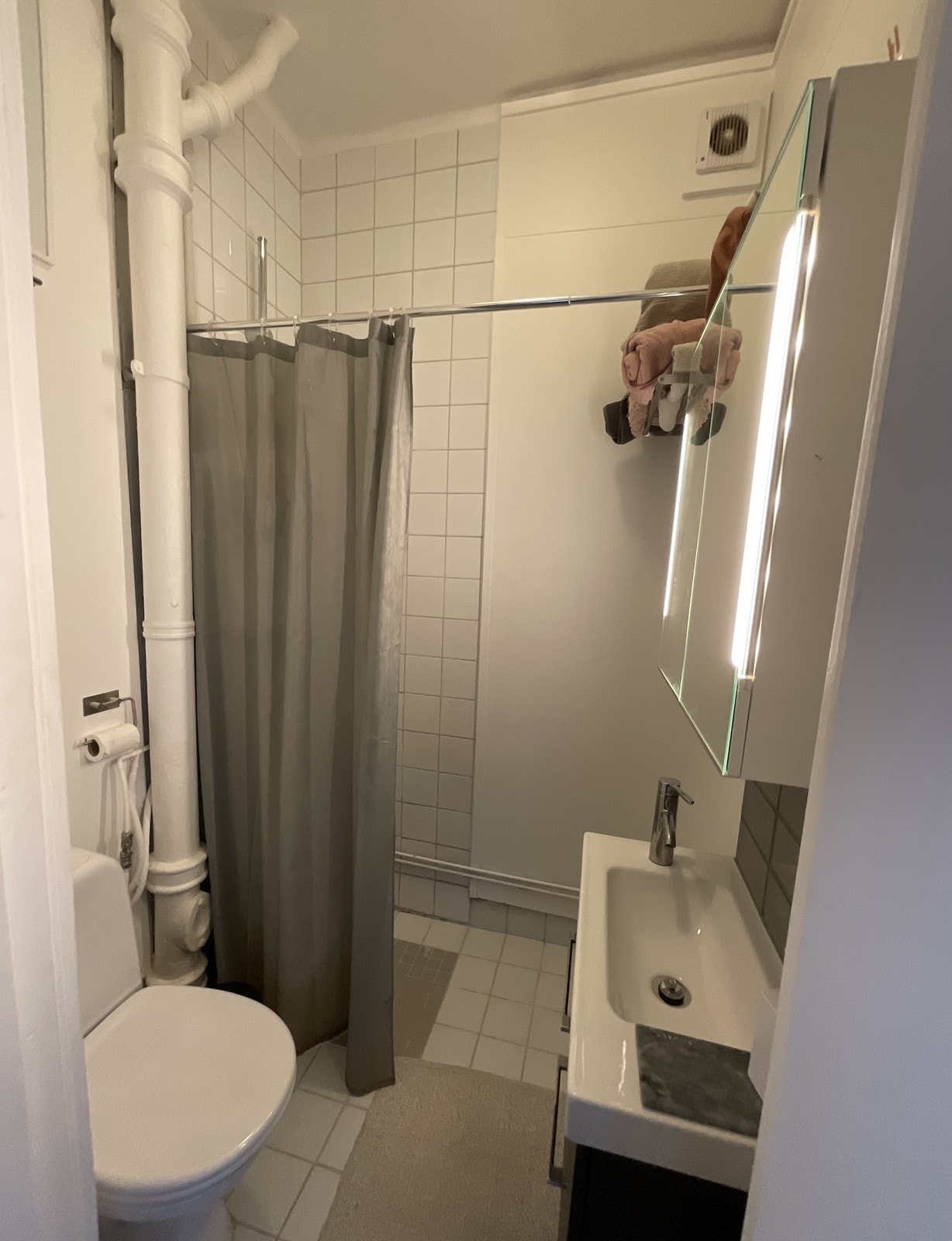 Bad med nyere servantskap og speilskap montert på vegg. Galleribilde