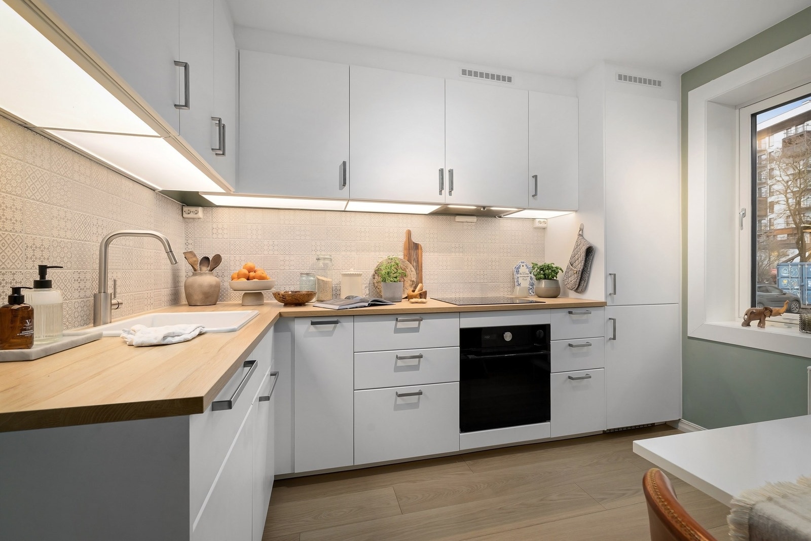 Innredning med slette, hvite fronter, benkeplater av laminat og nedfelt oppvaskkum med ett-greps armatur Galleribilde