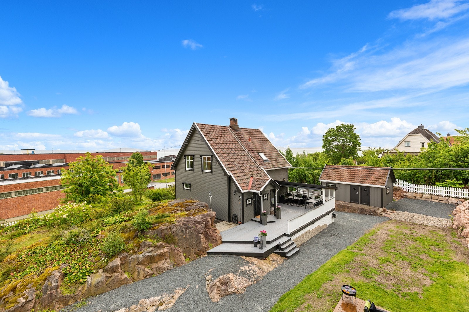 Stor vestvendt terrasse med uthuset i bakgrunn. Galleribilde