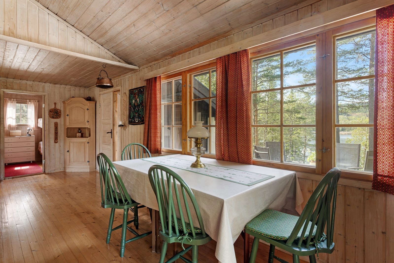 Gulv, vegger og himlinger har overflater av tre, med furugulv og trepanel på både vegger og himling. Galleribilde