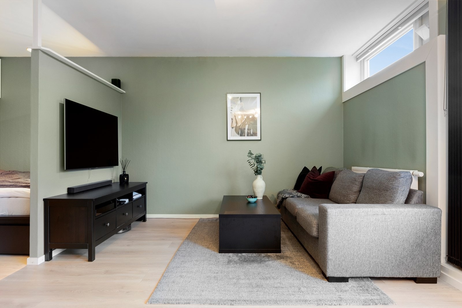 Her er det plass til sofa, spisebord og tv-møblement. Radiatoren i stua henter varme fra borettslagets sentralfyr og er ny fra 2021. Galleribilde