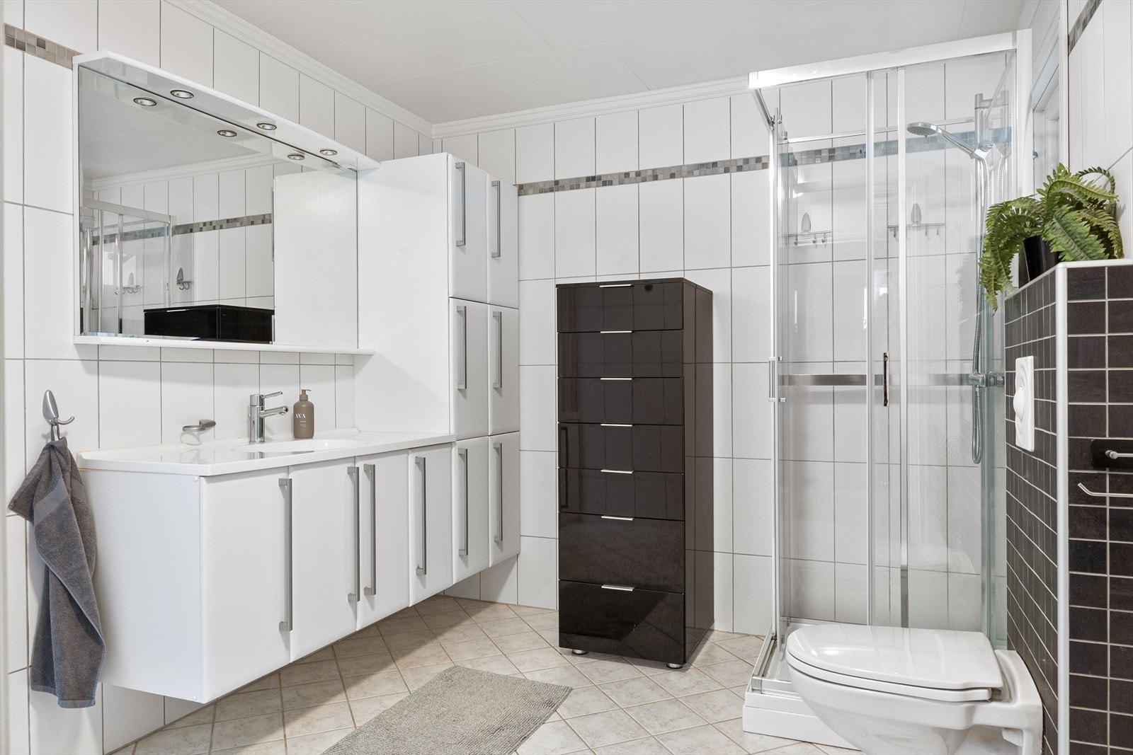 Badet er innredet med servant i møbel, veggmontert toalett og dusjkabinett. Galleribilde