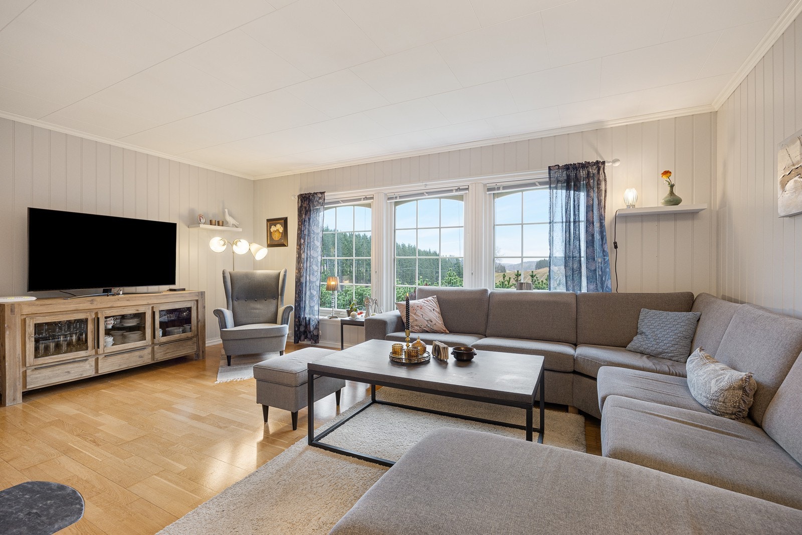 Parkett på gulvet kombineres med gråmalte panelplater på veggene. Galleribilde