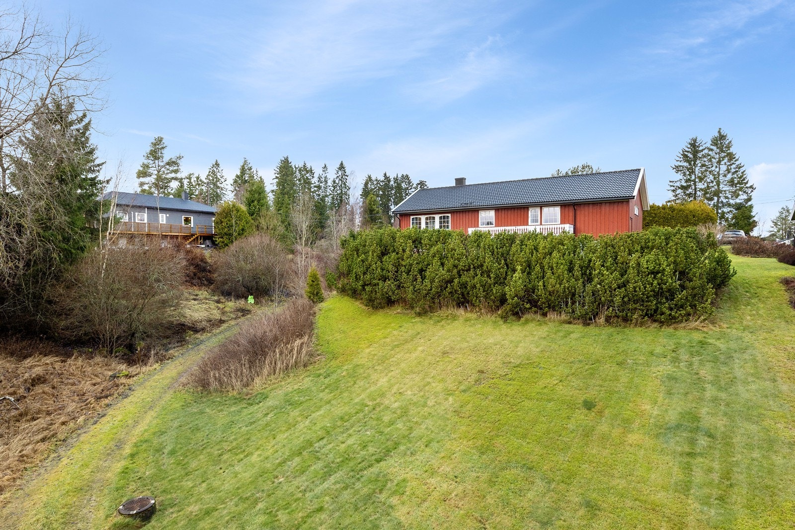 På inngangssiden har boligen en gruslagt gårdsplass, og hagen innbyr til lek for de yngste i familien. Galleribilde