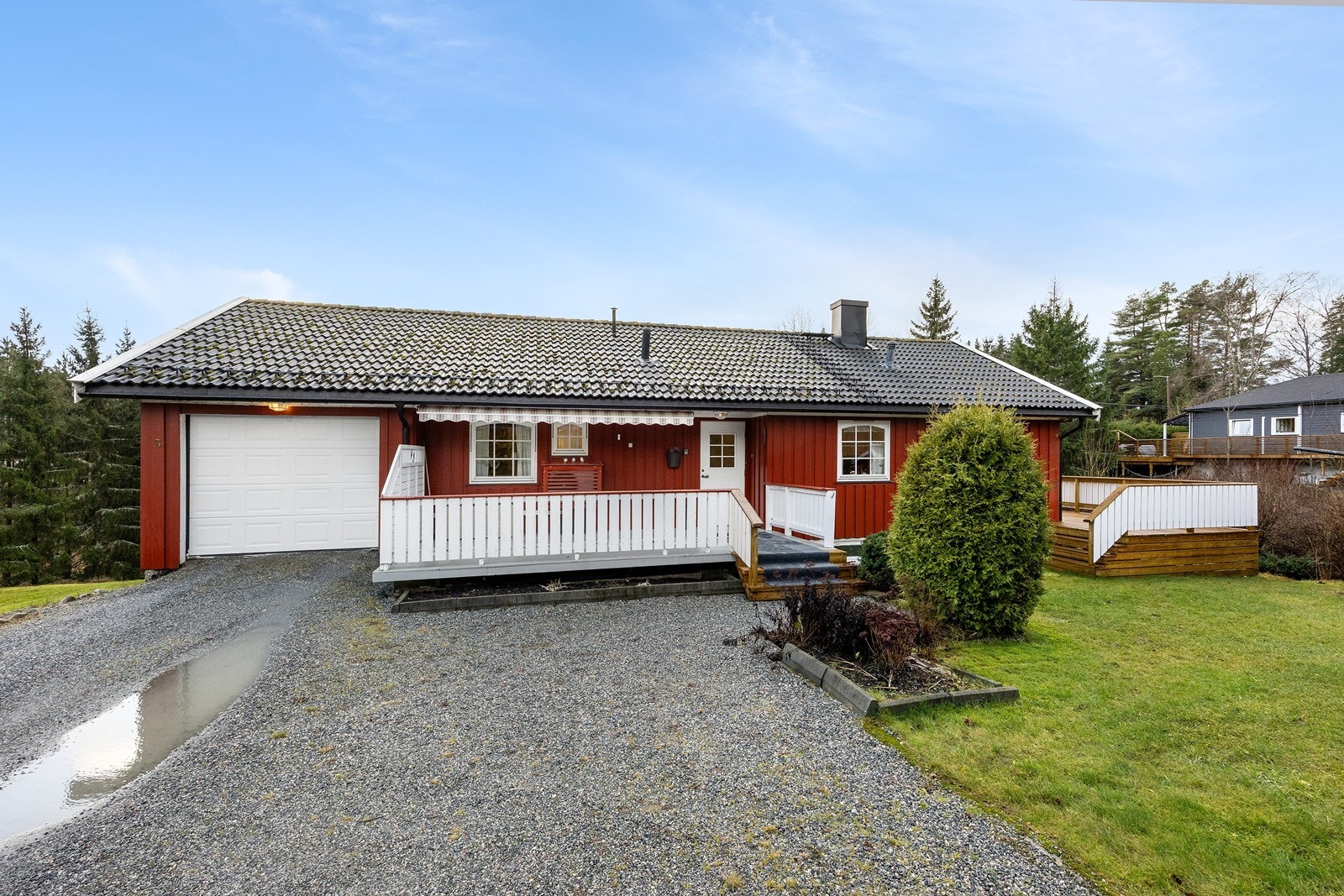 Eneboligen har en integrert garasje med elektrisk portåpner og et areal på ca. 19 kvm. Garasjen er platekledd innvendig, og foran huset finner man en gruslagt gårdsplass for ytterligere parkering. Galleribilde