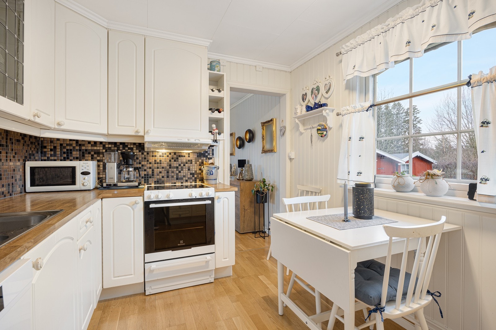 Innredningen har hvite, profilerte fronter, vitrineskap, dobbel oppvaskkum og benkeplate av laminat. Opplegg for oppvaskmaskin er etablert. Galleribilde