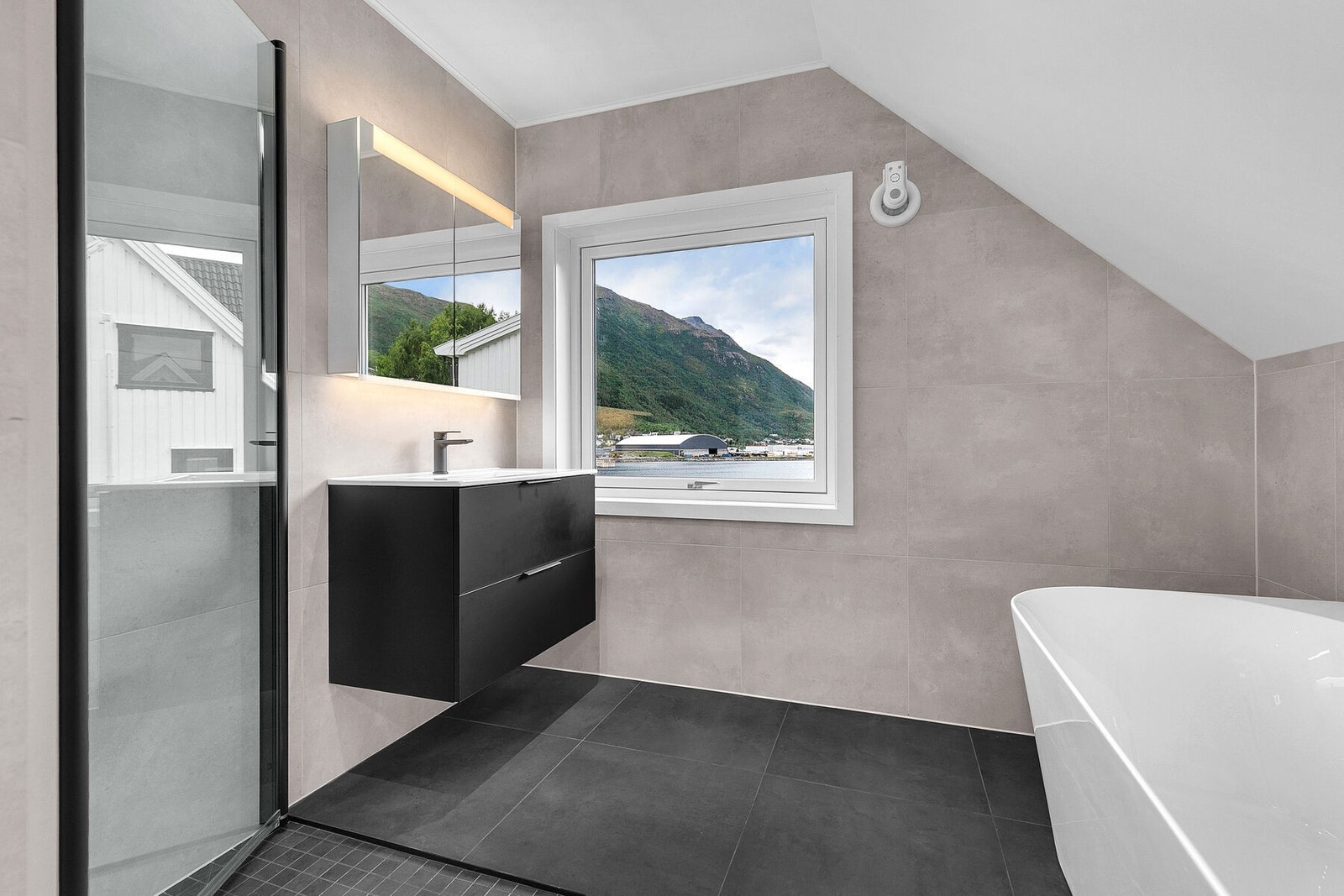 Lekkert bad med fliser på gulv og vegg, varmekabler, badekar og dusjnisje. Galleribilde