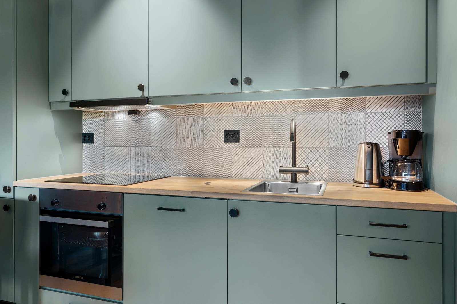 Kjøkkenet har en moderne innredning levert av Grønvold Snekkerverksted med glatte fronter, heltre benkeplate og integrerte hvitevarer fra Siemens og Røroshetta. Galleribilde