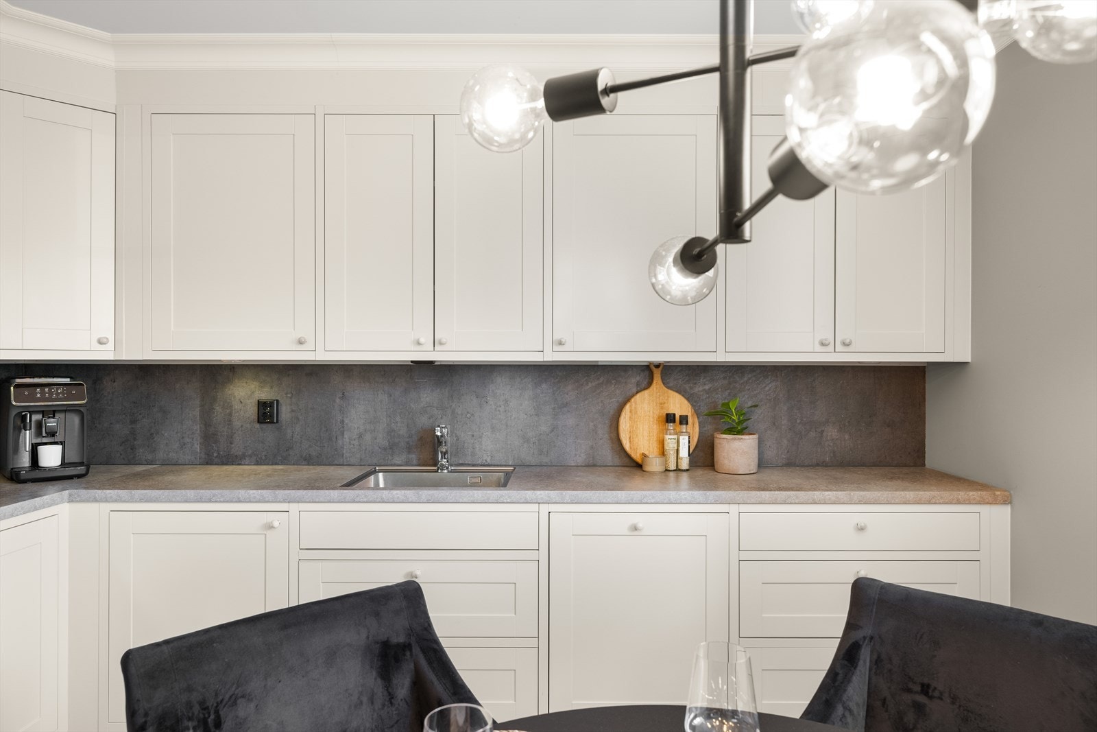 Klassisk og elegant kjøkkeninnredning med hvite profilerte fronter og benkeplate av laminat. Galleribilde