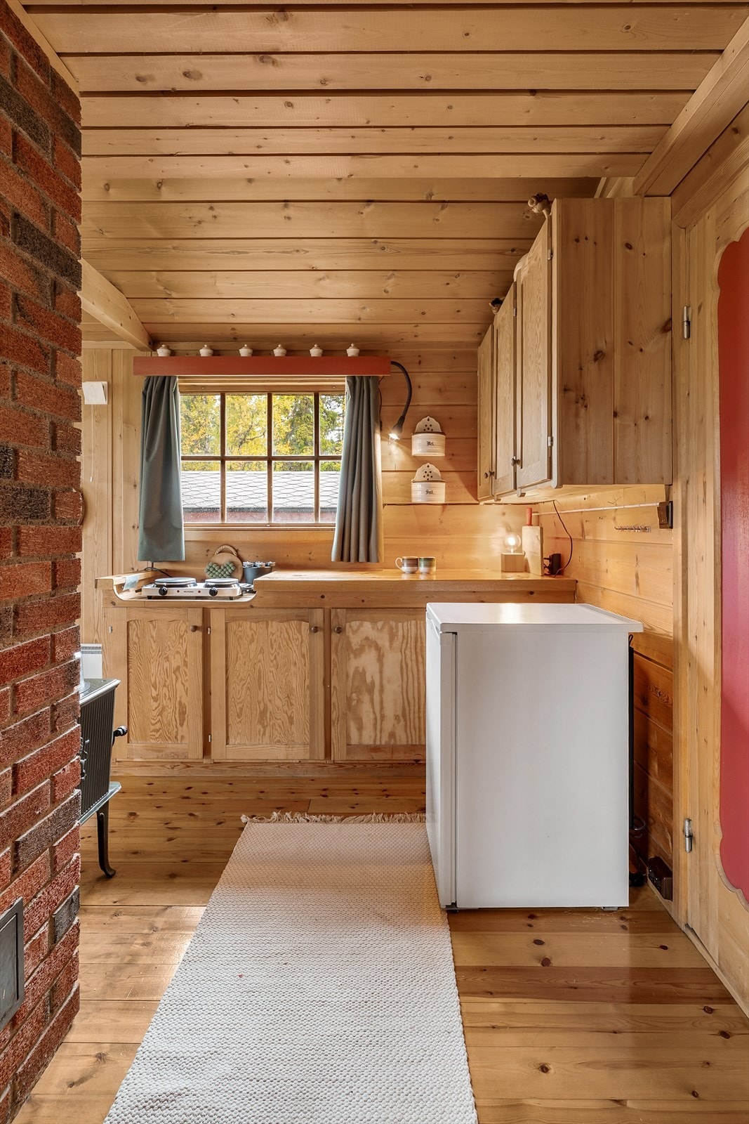 Kjøkkenet er enkelt innredet med innredning og benkeplate av heltre, og frittstående koketopp og kjøleskap. Galleribilde