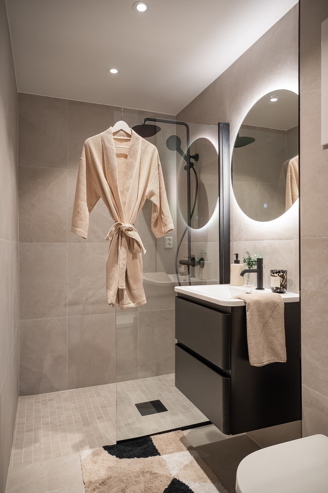 Nyoppusset bad som har 60x60 flis på gulv og vegger, dusjsone med waterfall dusj, sort servant med skap, belysning i speil, spotter i tak og varmekabler i gulv. Galleribilde