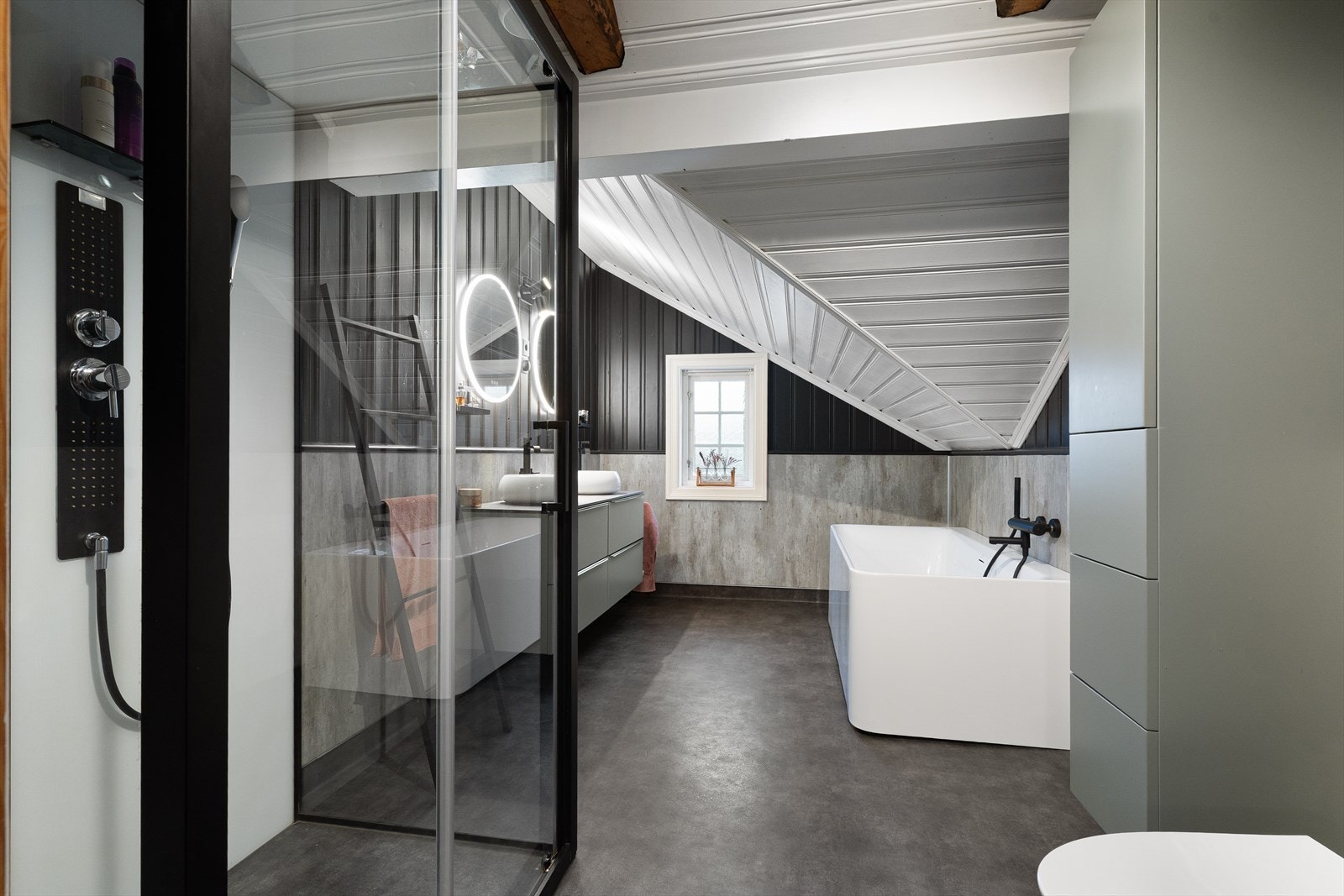 Badet inneholder innredning med skuffer og to toppmonterte servanter, toalett, badekar og dusjhjørne. Galleribilde